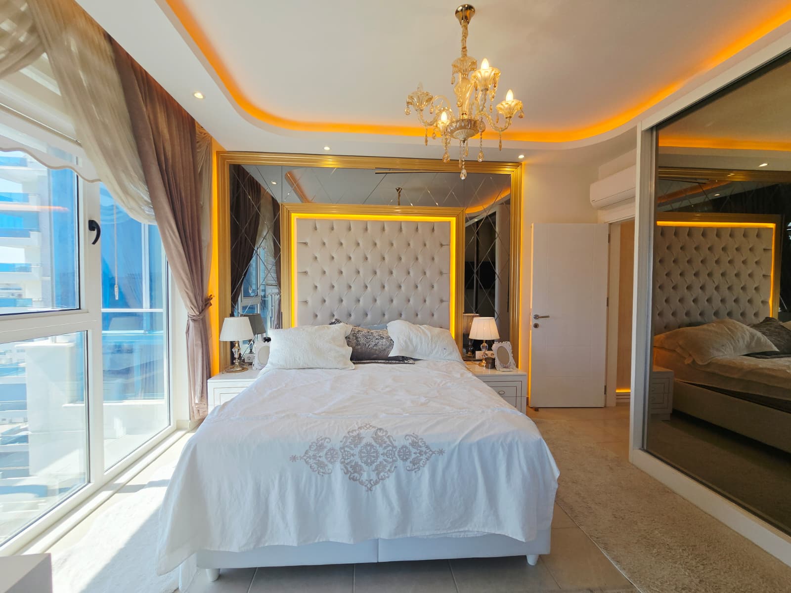 Yüksek kapitoneli başlıklı çift kişilik yatak ve kristal avize Mahmutlar’daki penthouse yatak odasında