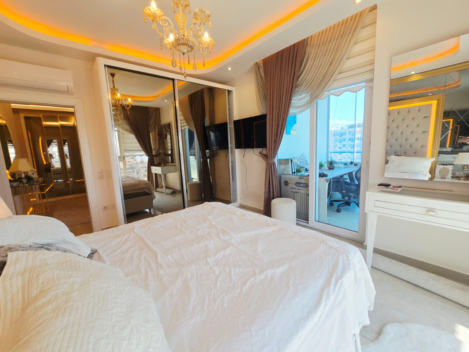Çift kişilik yatak, cam balkon kapısı ve aynalı gömme dolap Mahmutlar’daki yatak odasında