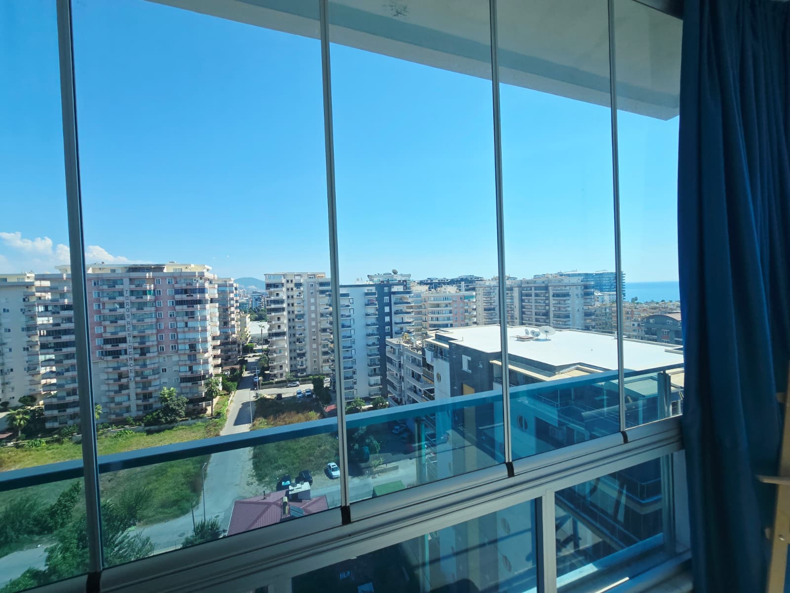 Panoramik camdan şehir yapıları ve ufuktaki deniz Türkiye’de satılık rezidanstan görülüyor