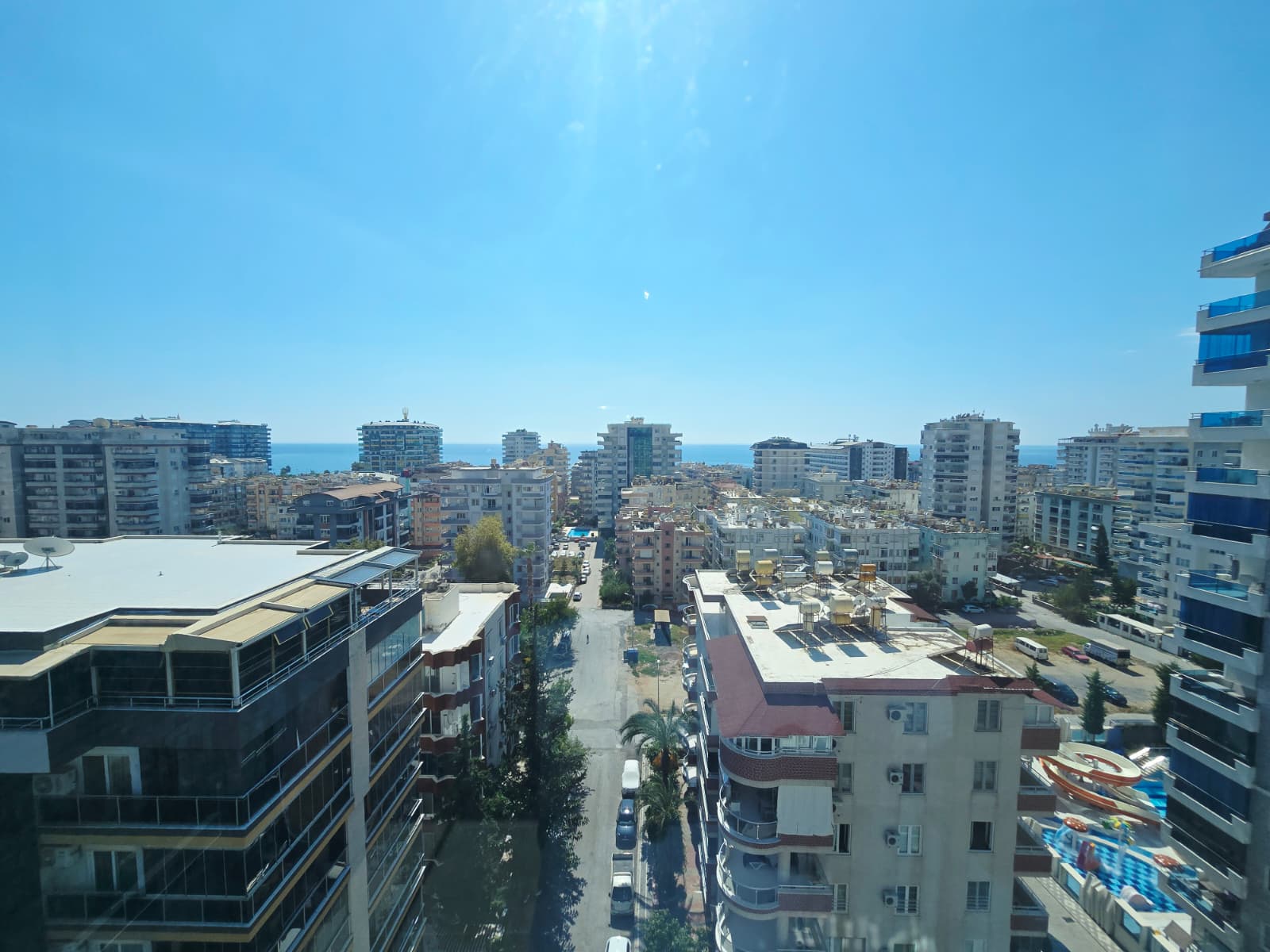 Mahmutlar’da şehir panoraması, ufukta deniz ve park edilmiş araçlar görülüyor