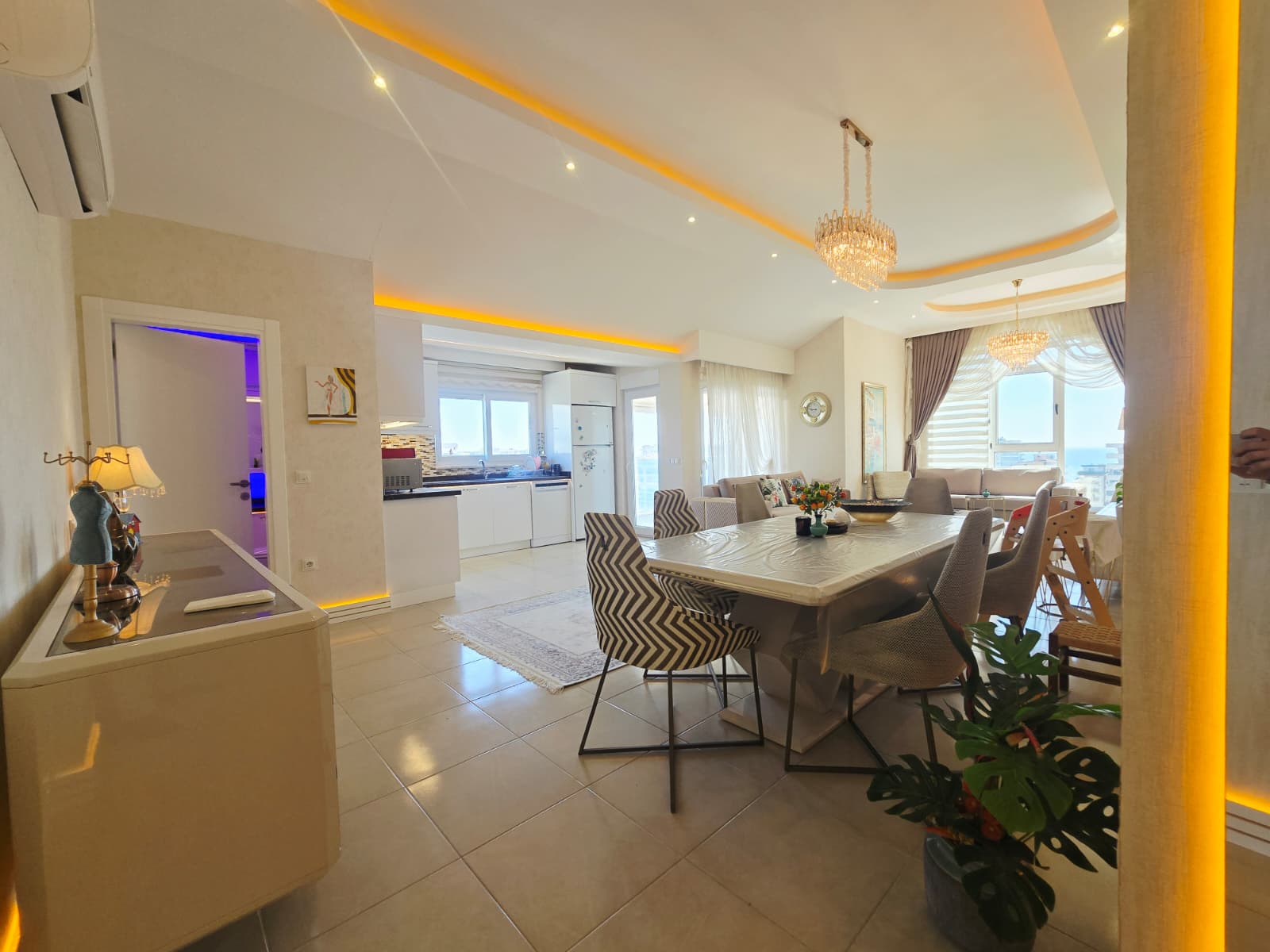 Dikdörtgen yemek masası, beyaz mutfak ve panoramik pencereler Mahmutlar’daki Türkiye penthouse’unda