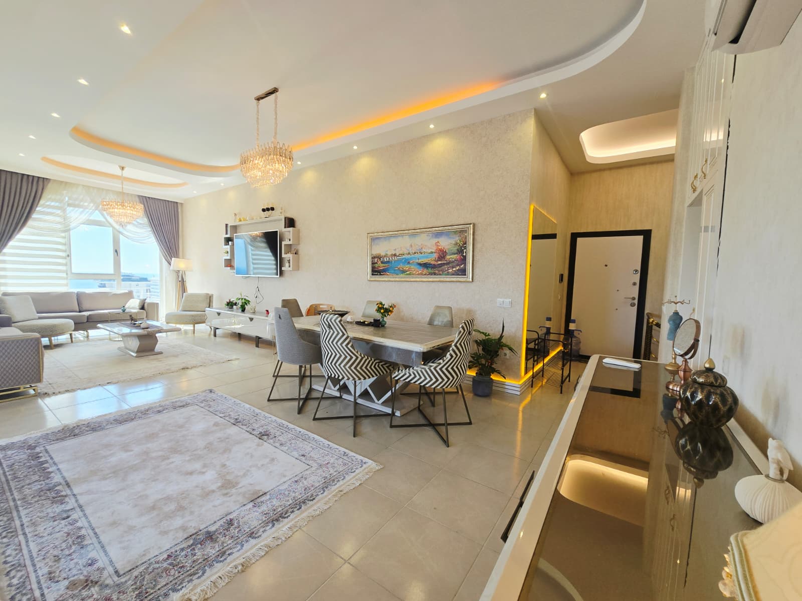 Açık plan aydınlık salon, yemek masası ve panoramik pencere satılık rezidansta