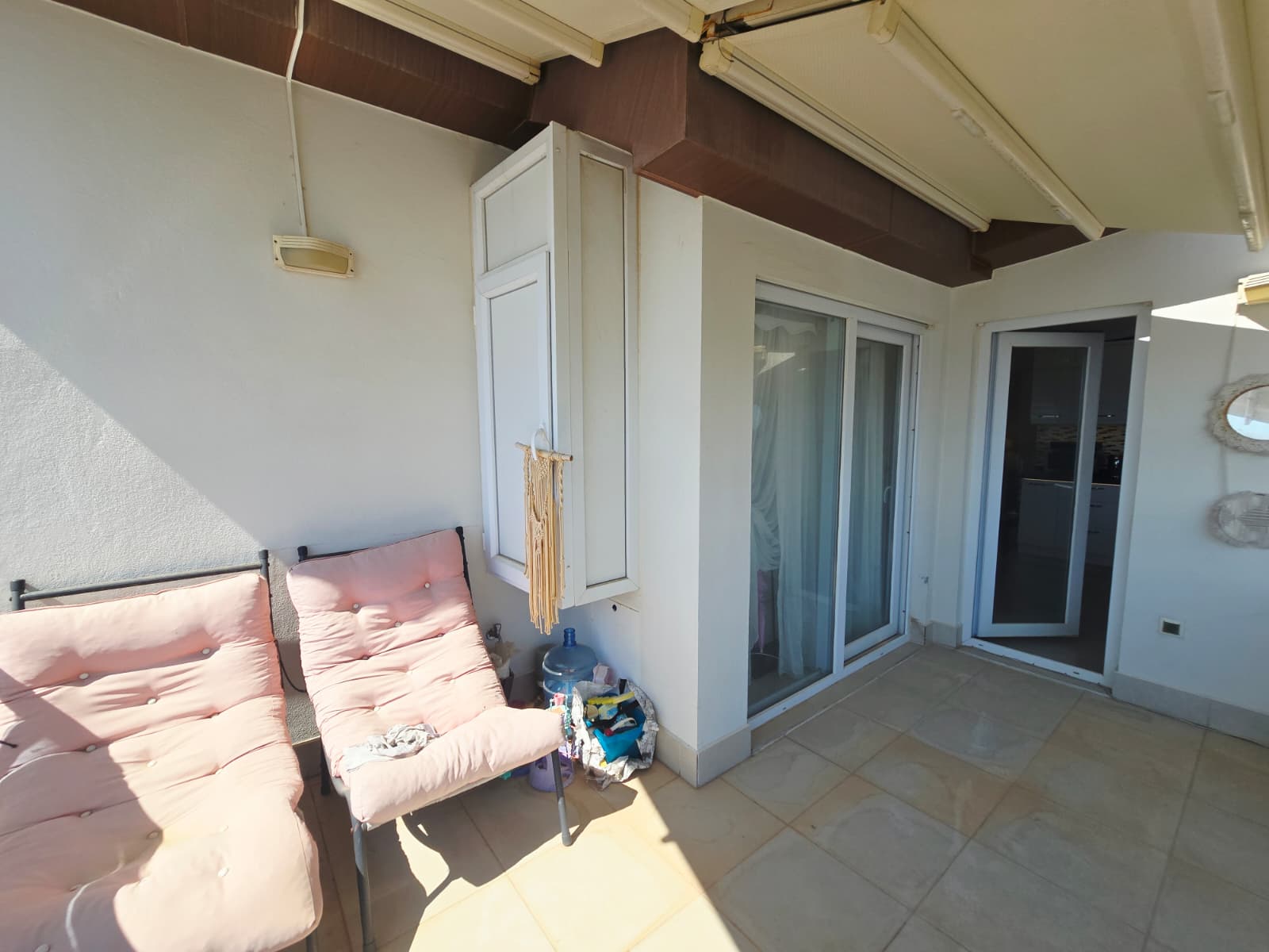Kapalı teras, pembe minderli sandalyeler ve sürgülü cam kapı Mahmutlar’da satılık penthouse’da