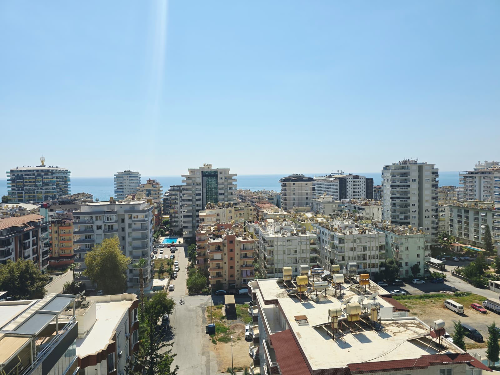 Panoramik şehir manzarası, ufuktaki deniz ve yeşil ağaçlar penthouse içinden