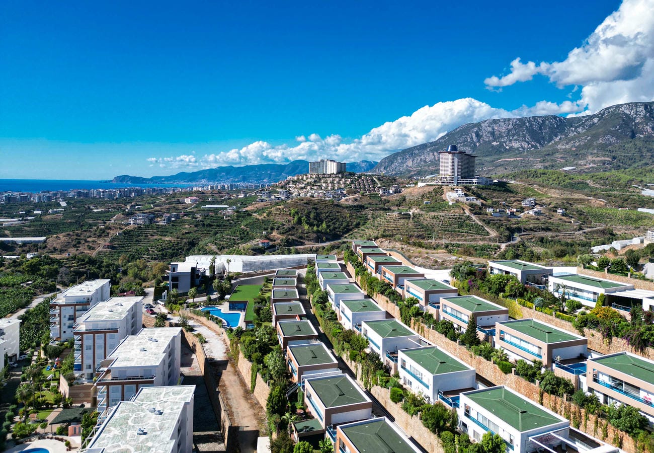 Aerial row of green-roof villas and a central pool in a complex with villas for sale in Turkey