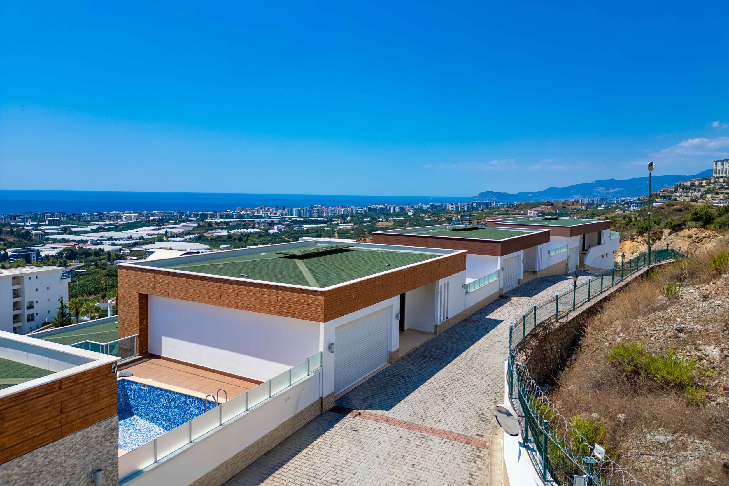 Green-roof villas with a nearby pool and fenced paved road in Kargicak, Turkey