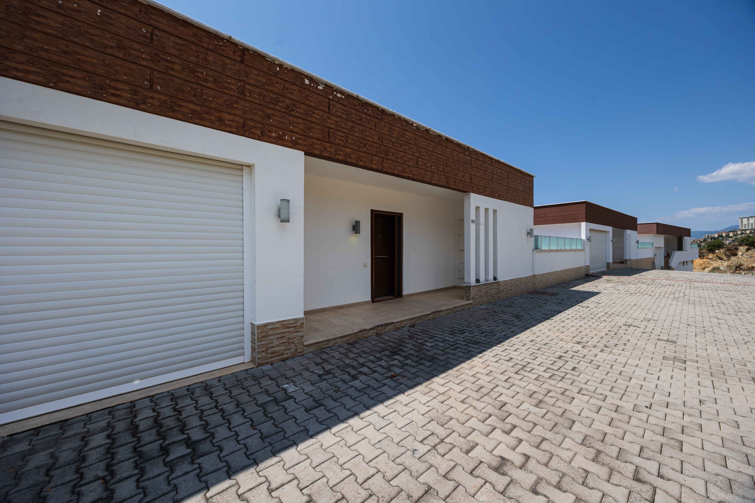 White villa facade with covered entrance and closed garage doors in Turkey for sale
