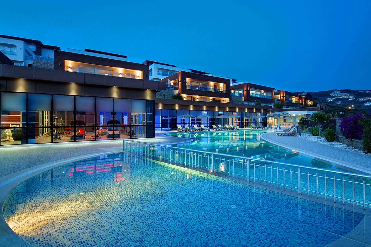 Open pool with loungers and evening lighting in a complex with villas for sale in Turkey