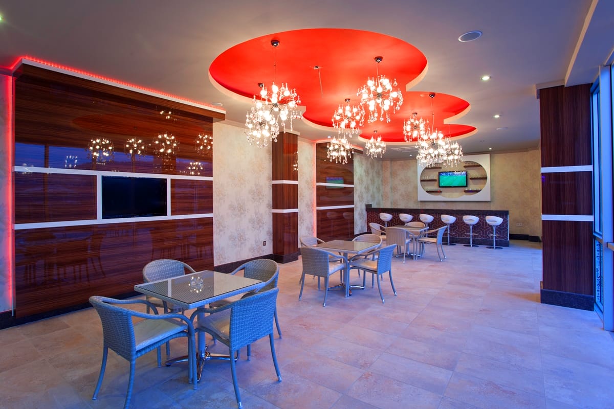 Dining tables, wicker chairs and a bar counter in a cafe within a complex with villas