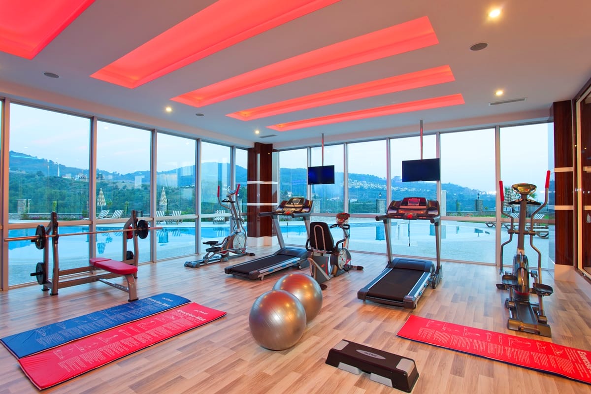 Treadmills, exercise bikes and a weight bench in a gym for residents of villas