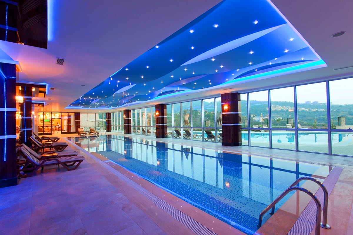 Indoor pool with loungers and blue lighting in a complex with villas for sale in Kargicak