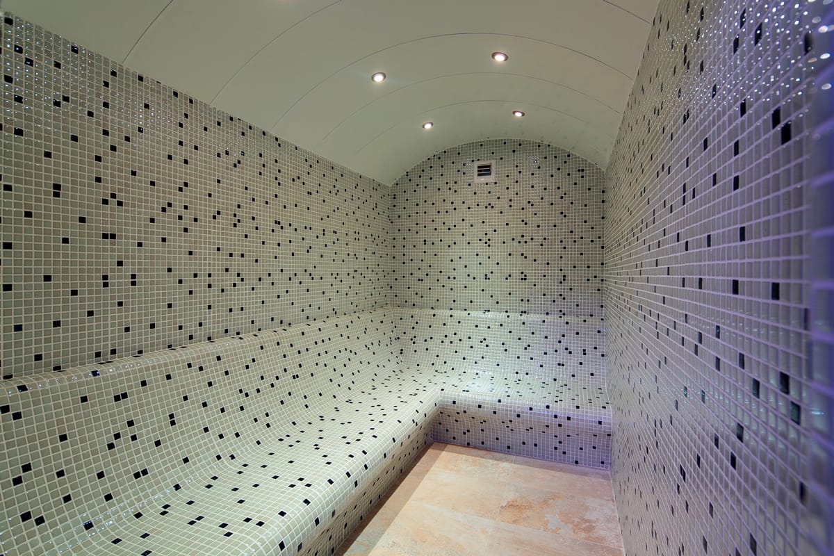 Steam room with mosaic benches, a vaulted ceiling and white-and-black walls in Kargicak