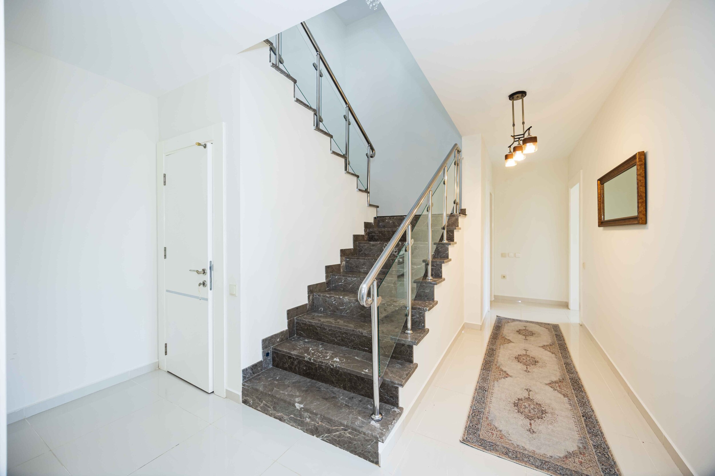 Staircase with dark stone steps and glass railings inside a house in Kargicak