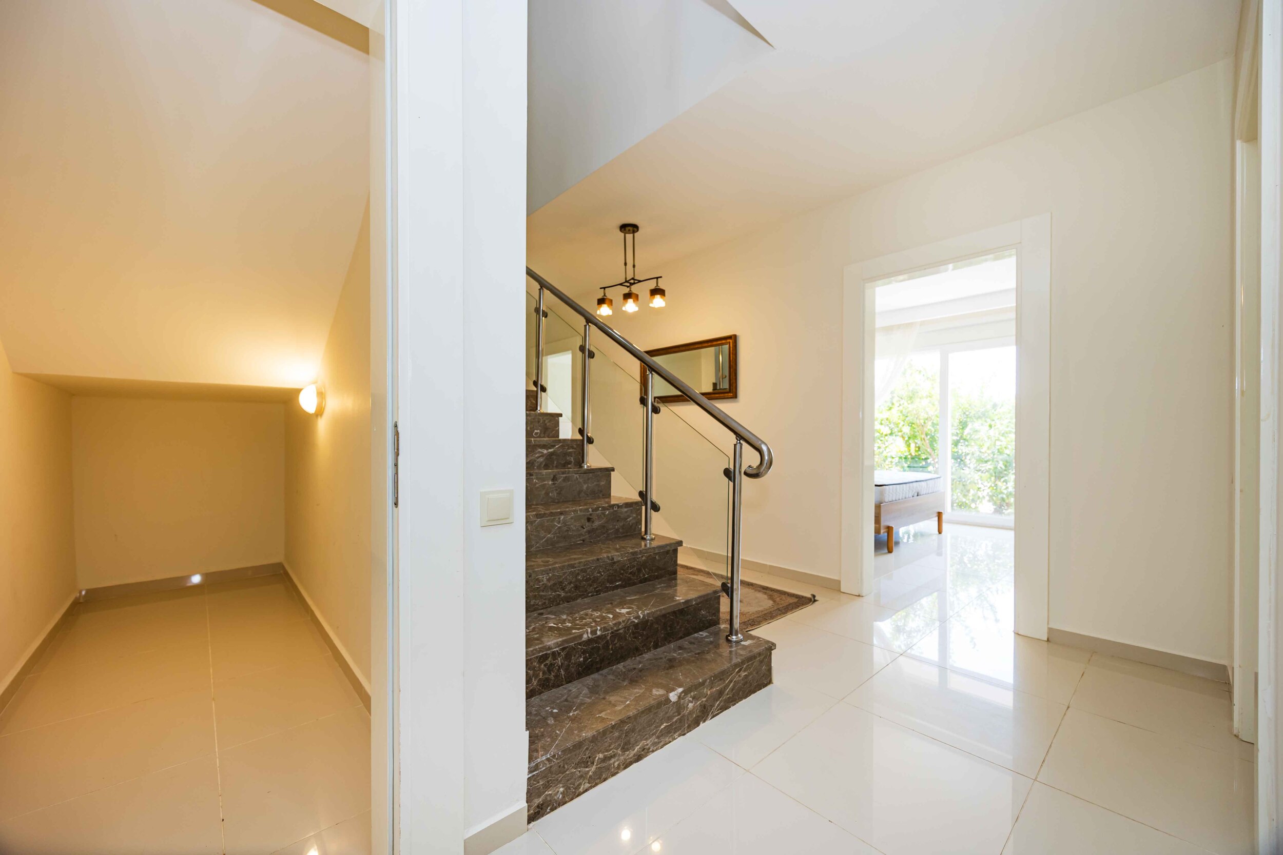Bright villa hall with a staircase and a window overlooking greenery