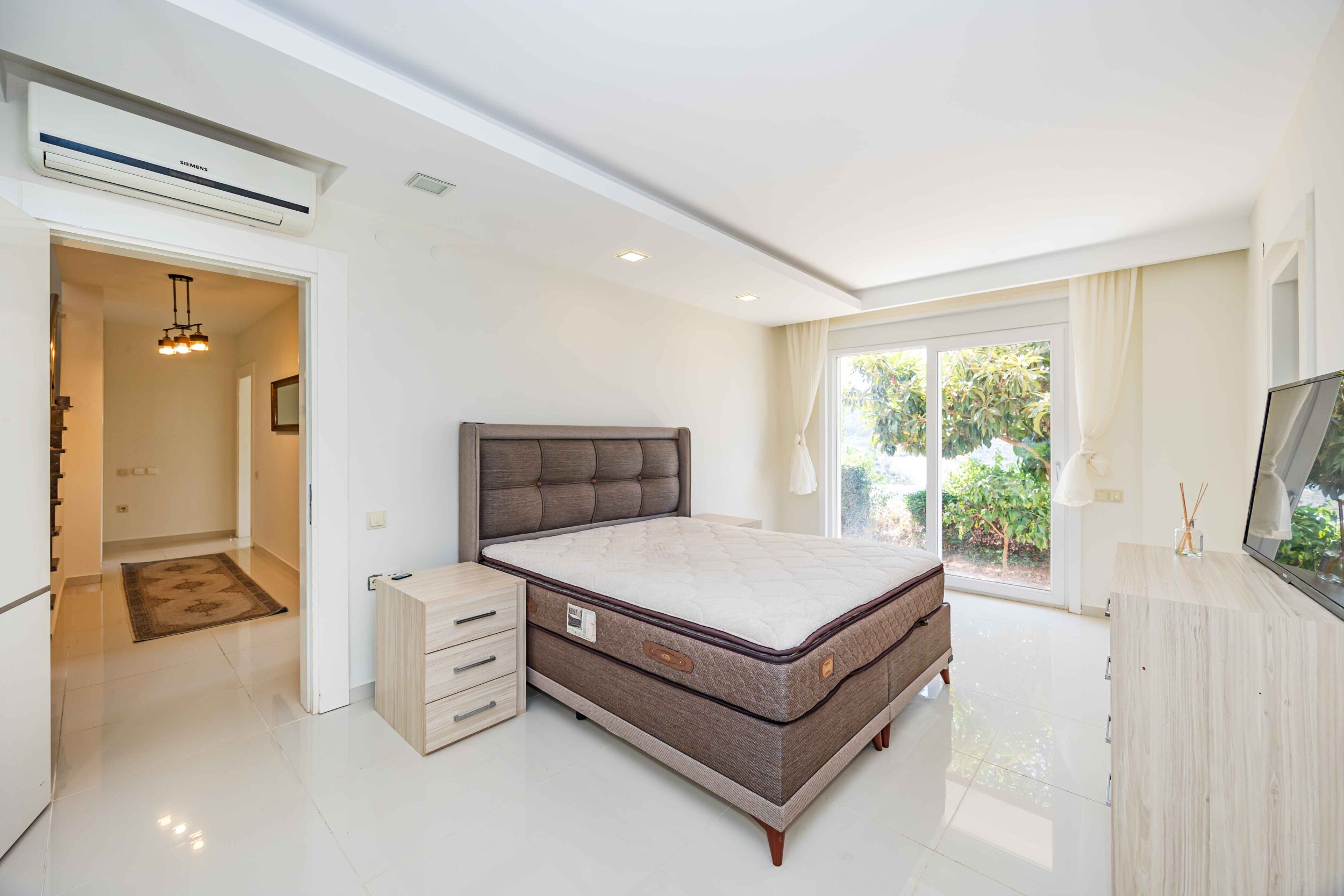 Bedroom with a bed, television and wide window overlooking greenery in a house in Kargicak