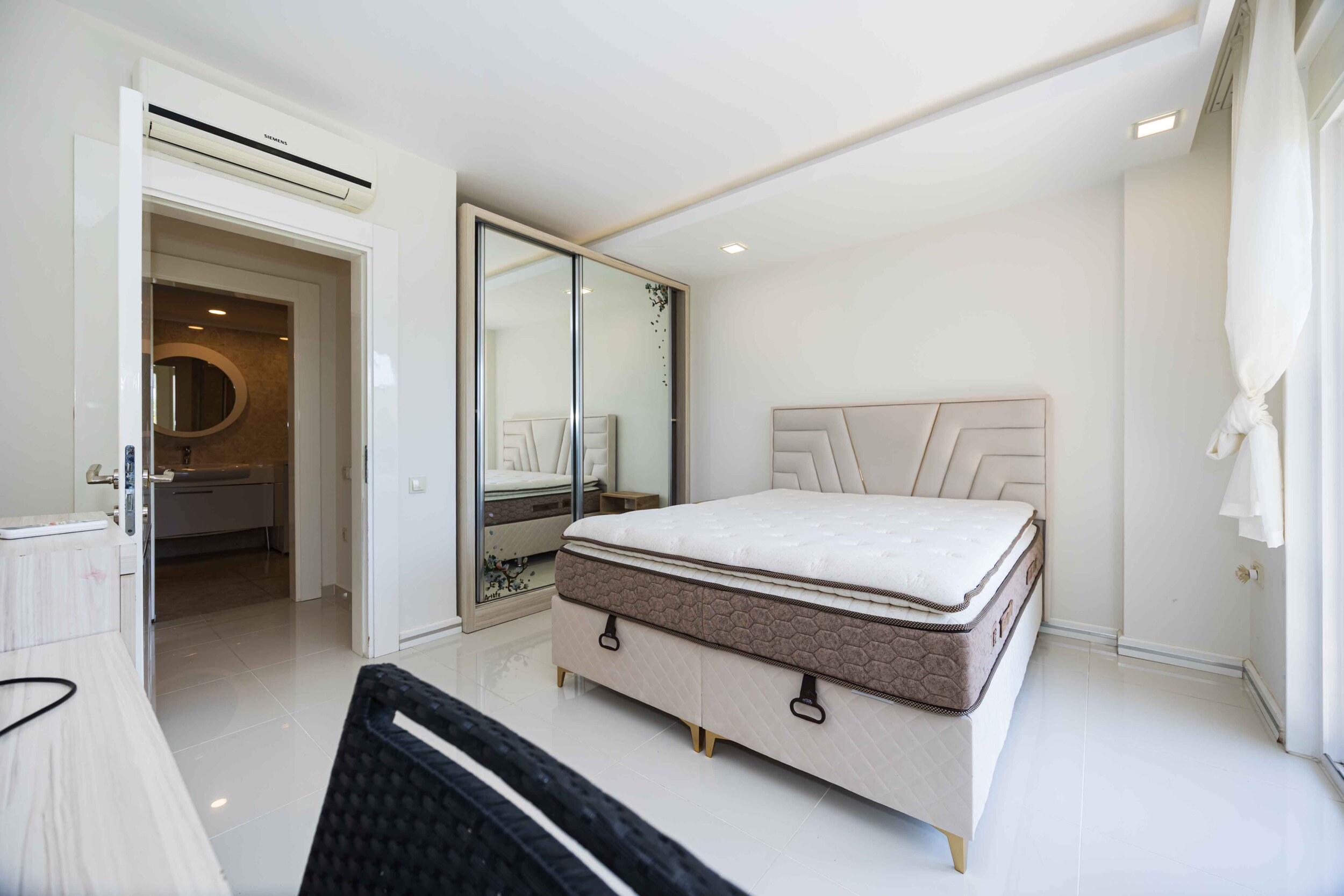 Bedroom with a white bed, built-in wardrobe and panoramic window in a house in Kargicak