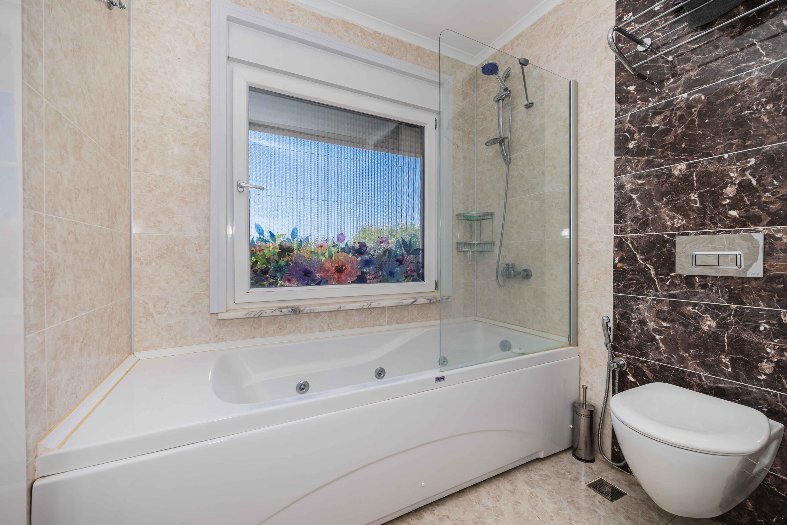 Bathroom with whirlpool tub, shower screen and brown marble tiles in a villa