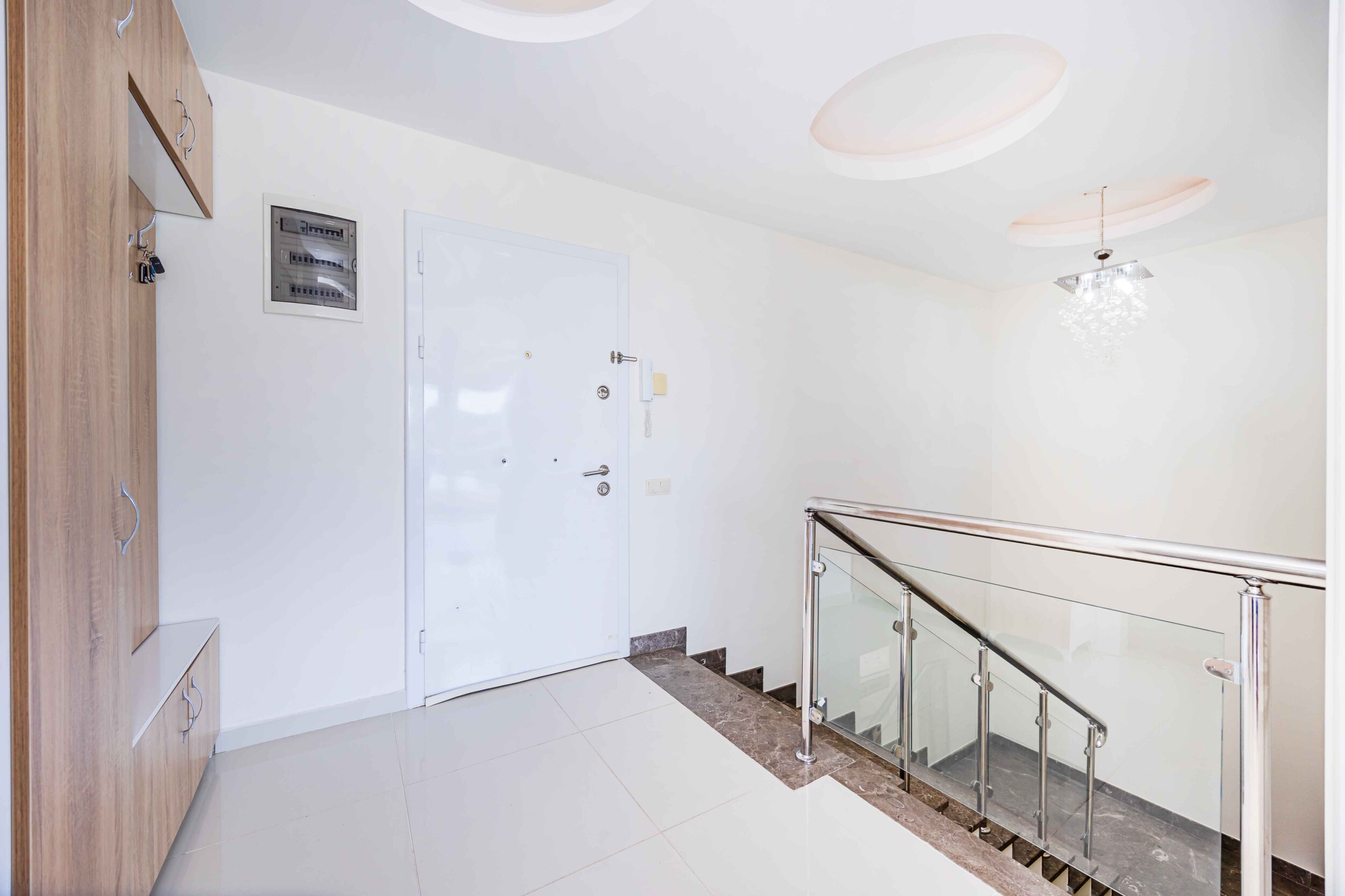 Landing by the stairs with a white door, glass railing and built-in wardrobe in a villa