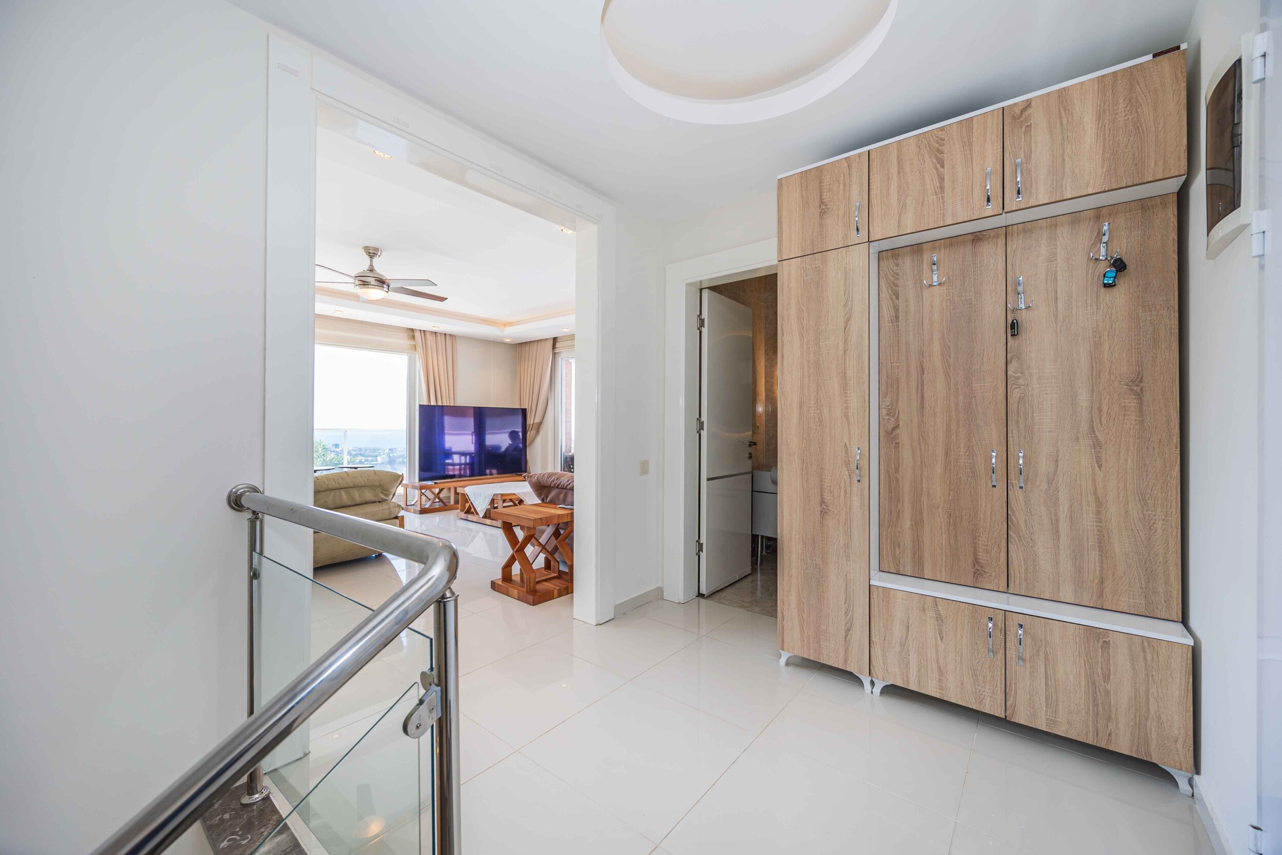Hall by the stairs with a wooden wardrobe and living room opening in a house in Kargicak