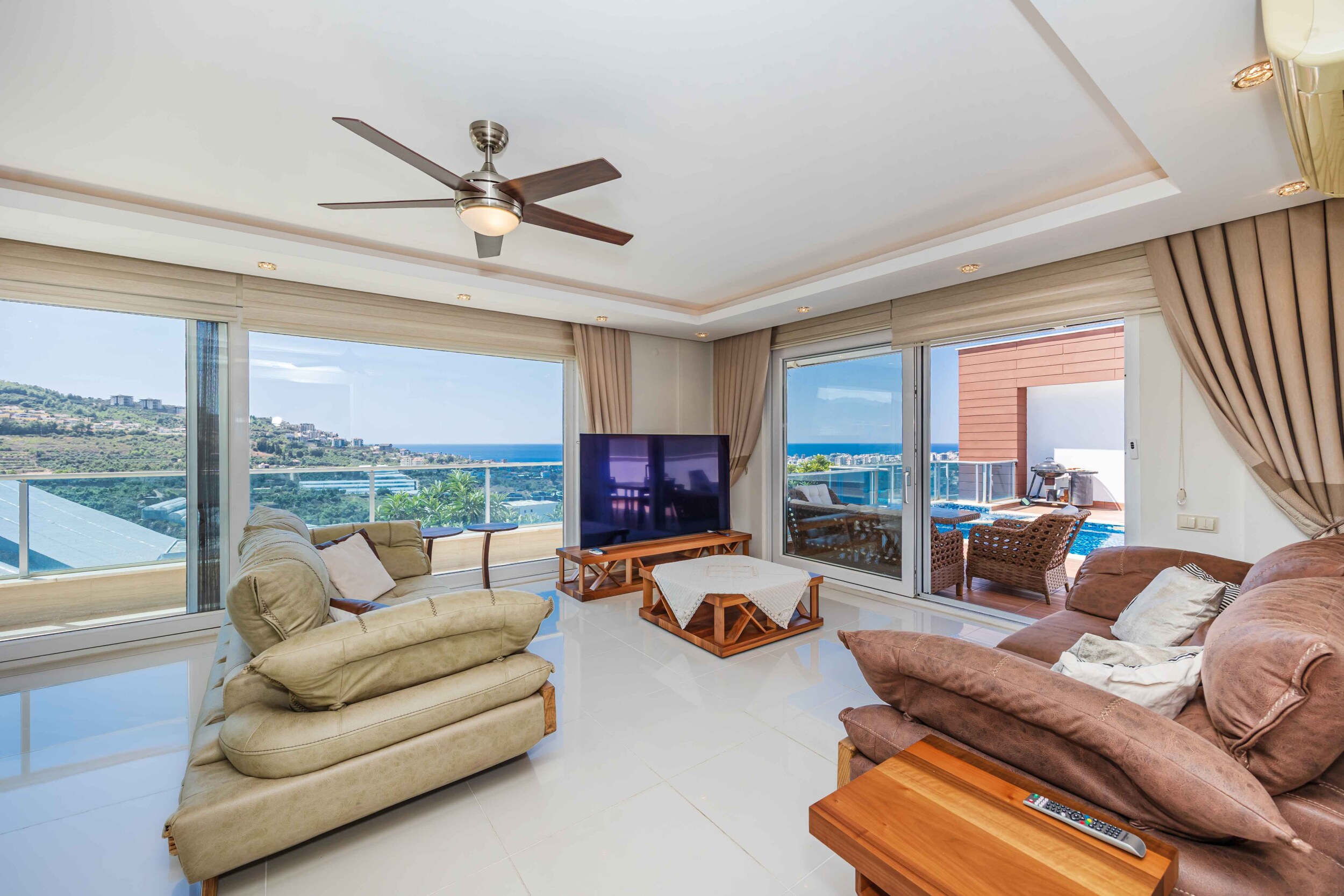 Living room with brown and light sofas and panoramic glazing in a villa in Turkey for sale