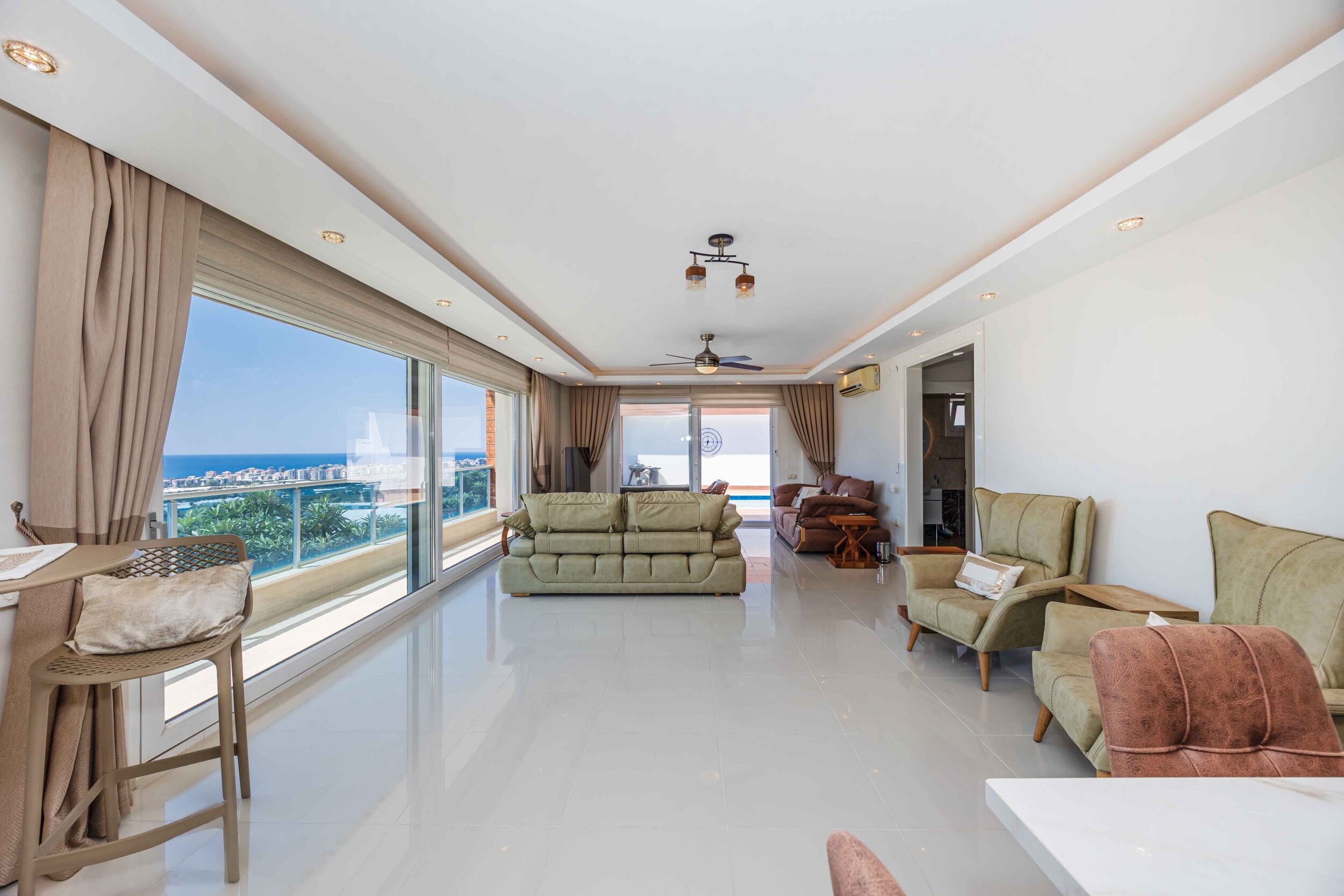 Light sofa, armchairs and dining table beside panoramic windows in a house in Turkey
