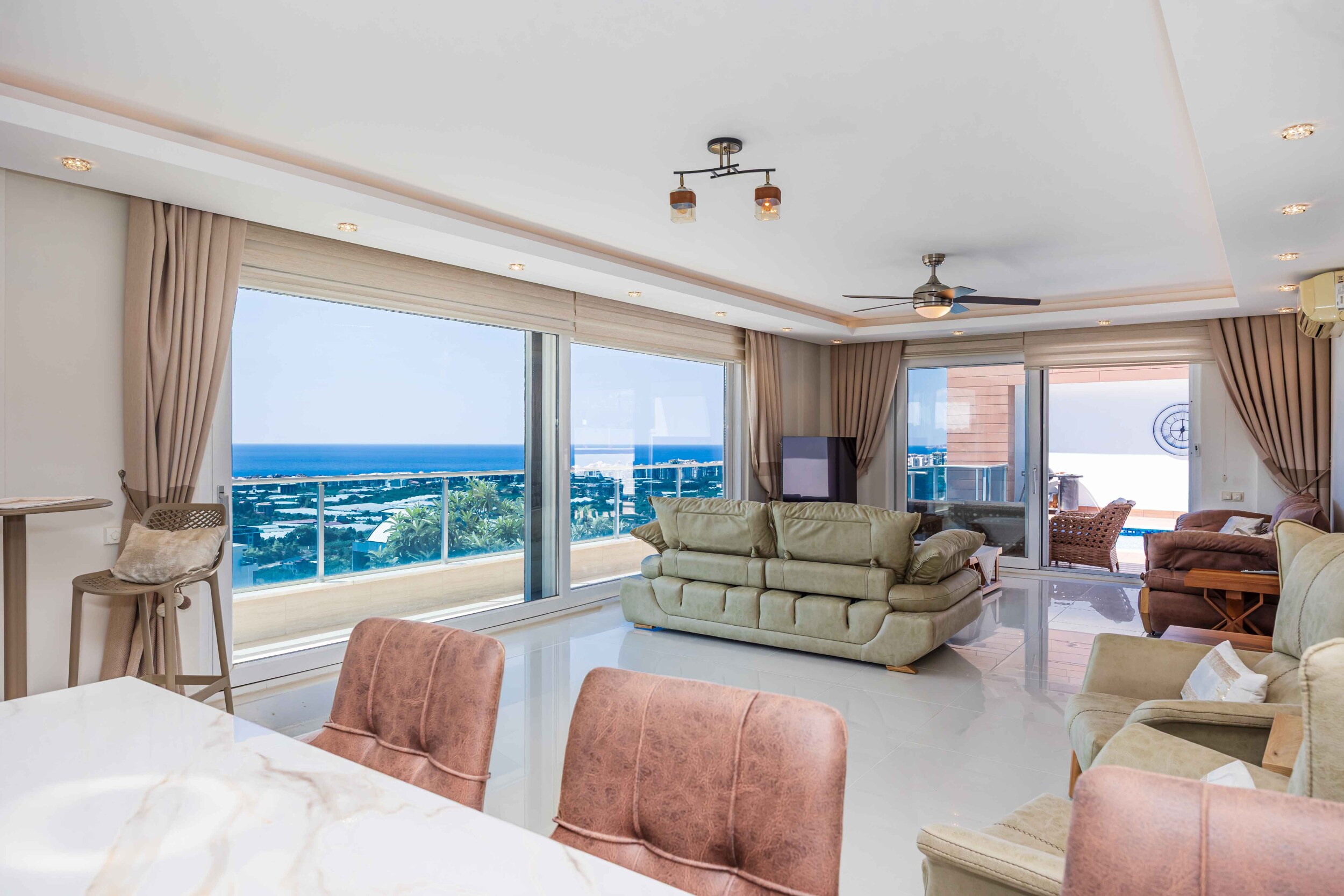 Light sofa and dining table with a sea and city view from the villa