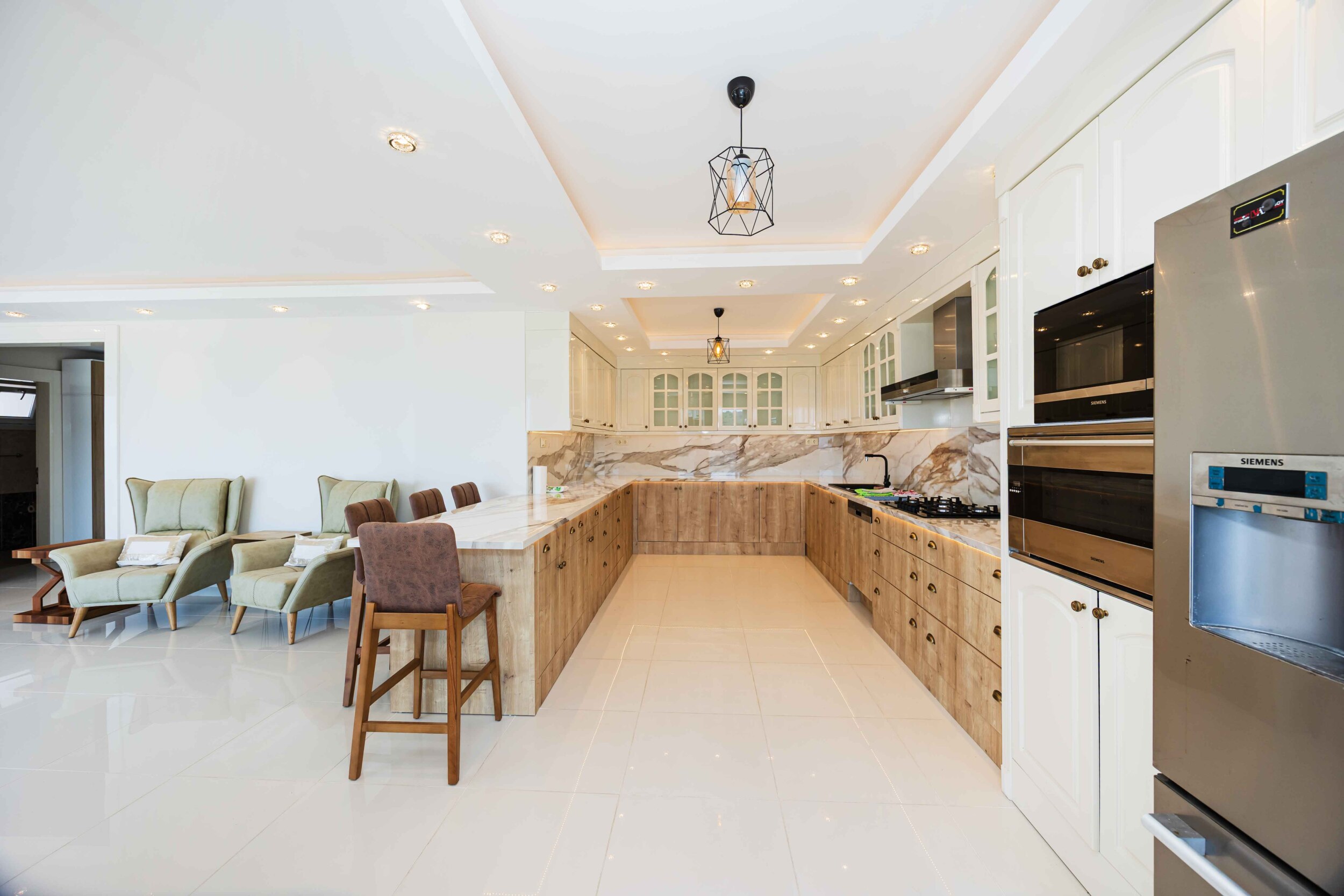 L-shaped kitchen with island, marble backsplash and bar stool inside the house
