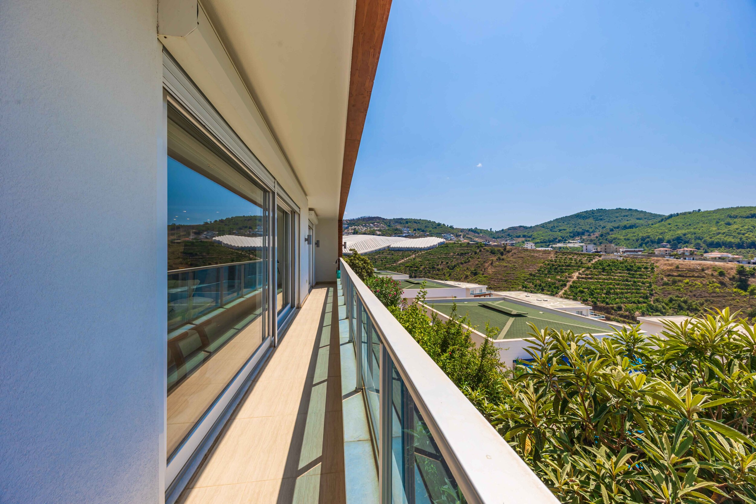 Narrow balcony with glass railings and hills beyond in Kargicak where villas are for sale