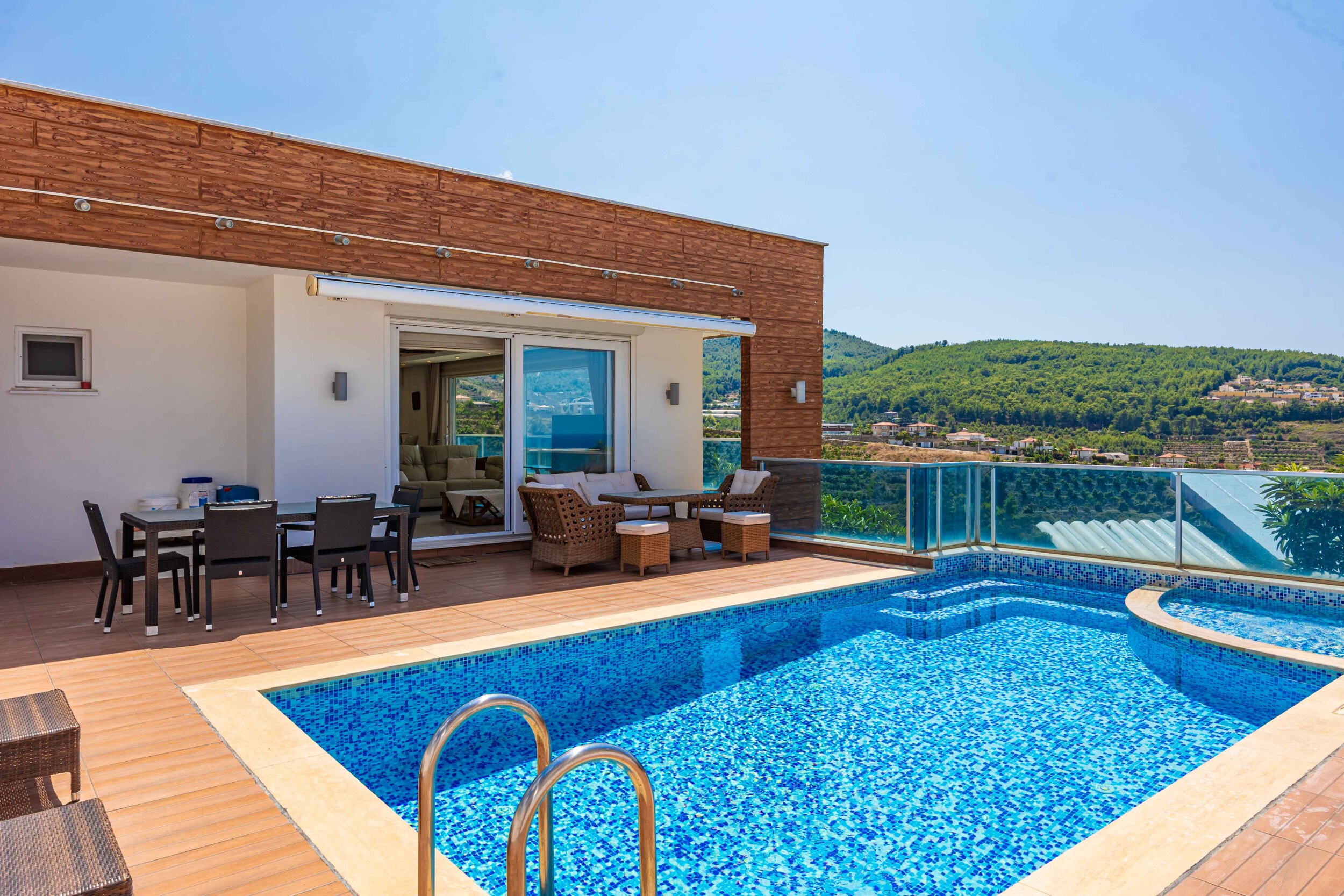 Mosaic-lined pool and seating area overlooking green hills beside a villa in Turkey for sale