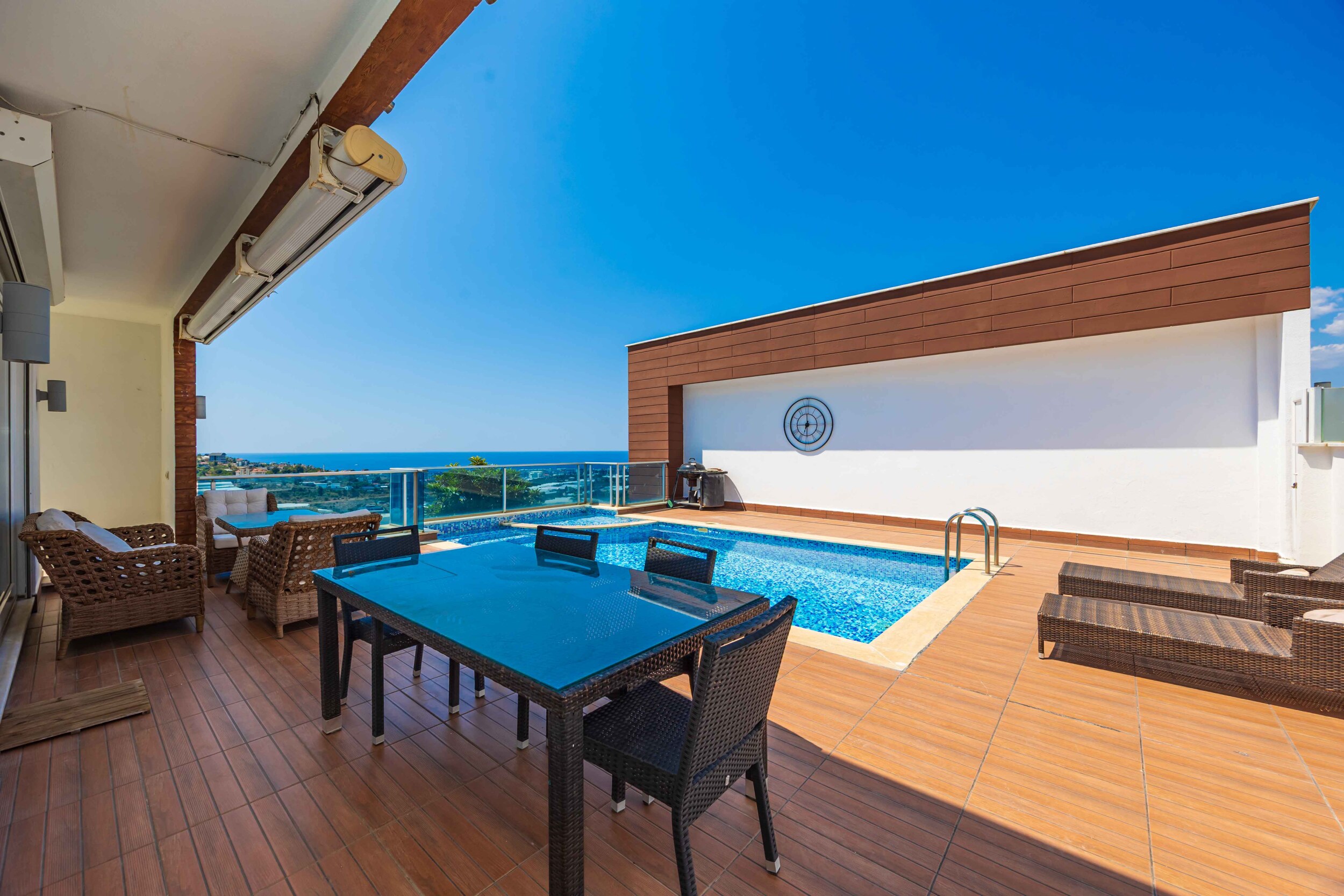 Pool, wooden terrace and covered seating area with sea views beside a villa in Turkey