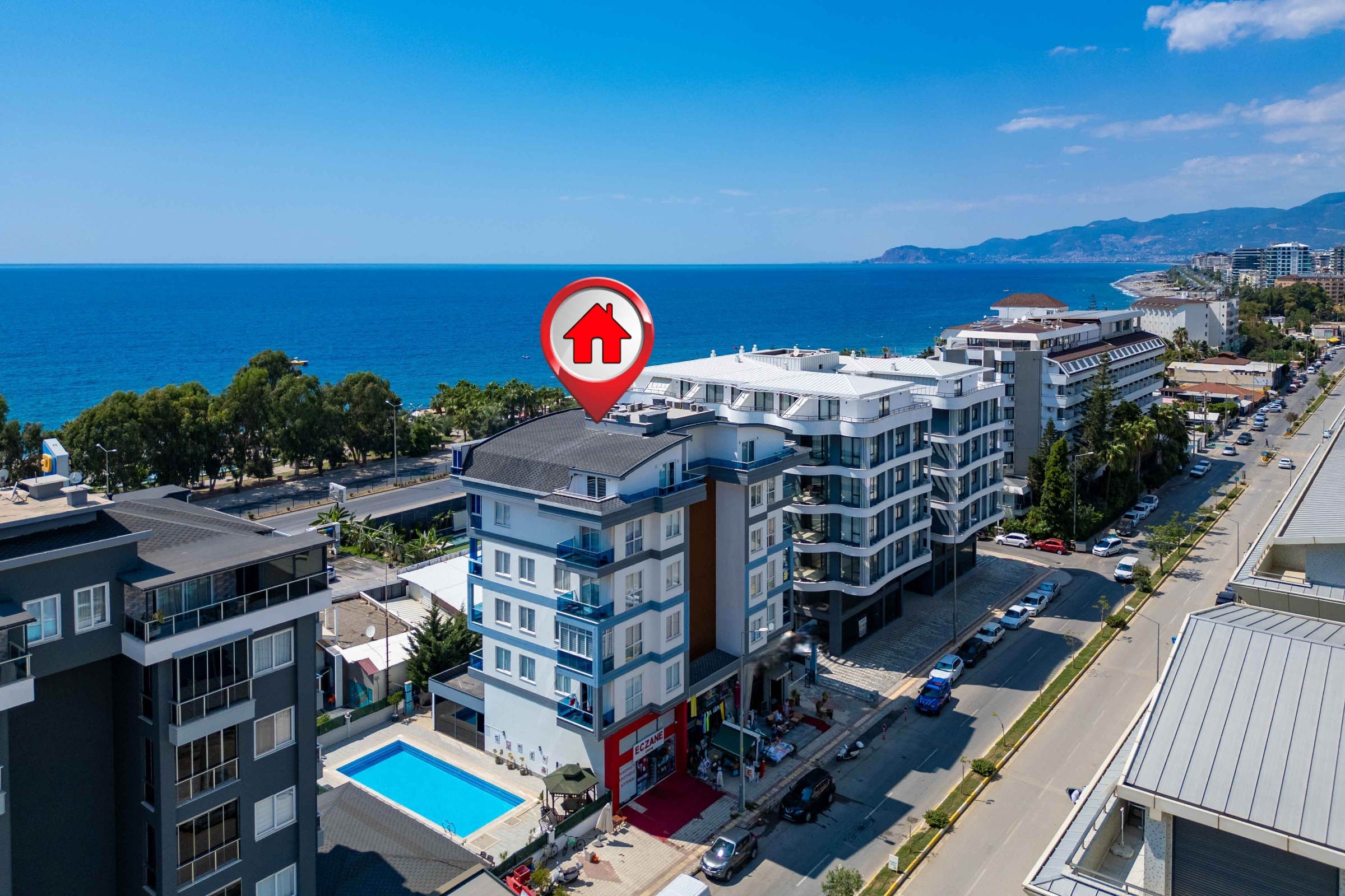Aerial view of a white complex with a pool by the sea: a 2+1 penthouse for sale in Kargicak, Alanya, Turkey — New Level Group