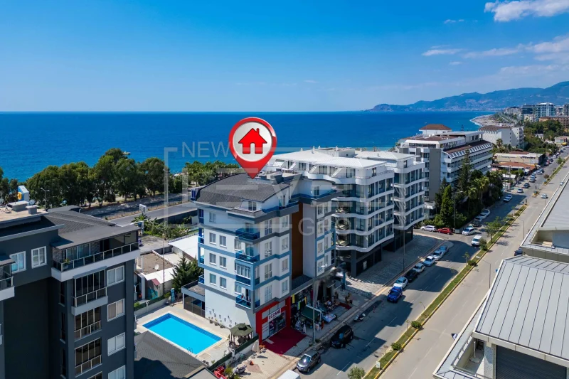 Aerial view of a white complex with a pool by the sea: a 2+1 penthouse for sale in Kargicak, Alanya, Turkey — New Level Group