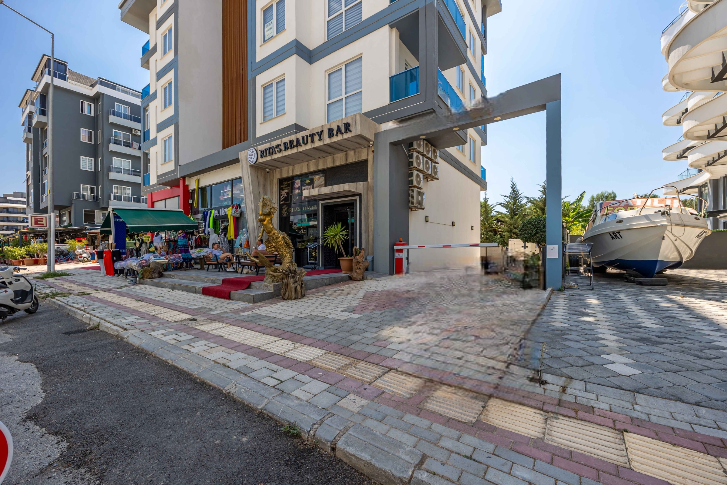 Ground-floor salon entrance and paved walkway beside a penthouse for sale