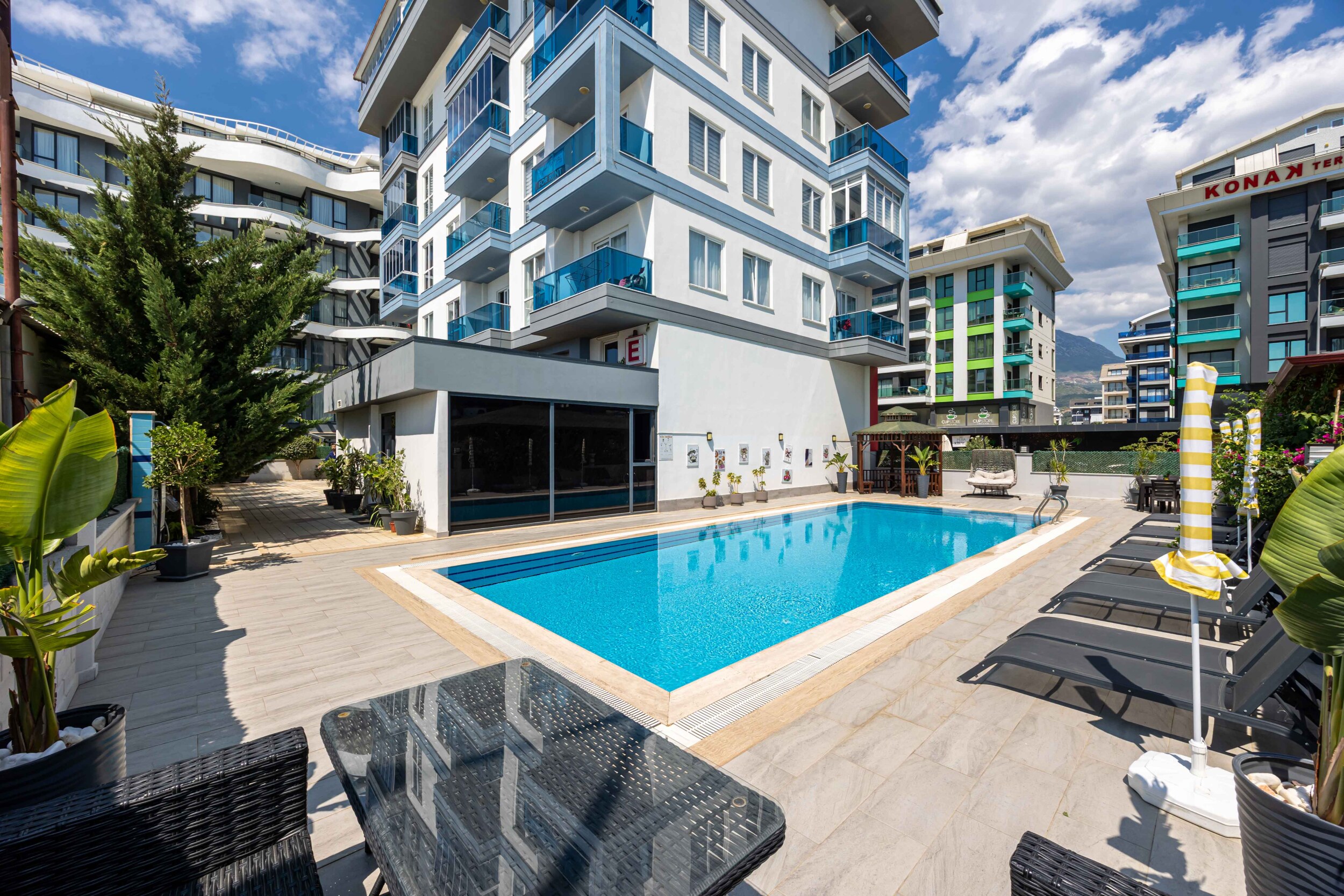 Open pool with loungers and wicker chairs at the complex in Turkey where apartments are for sale