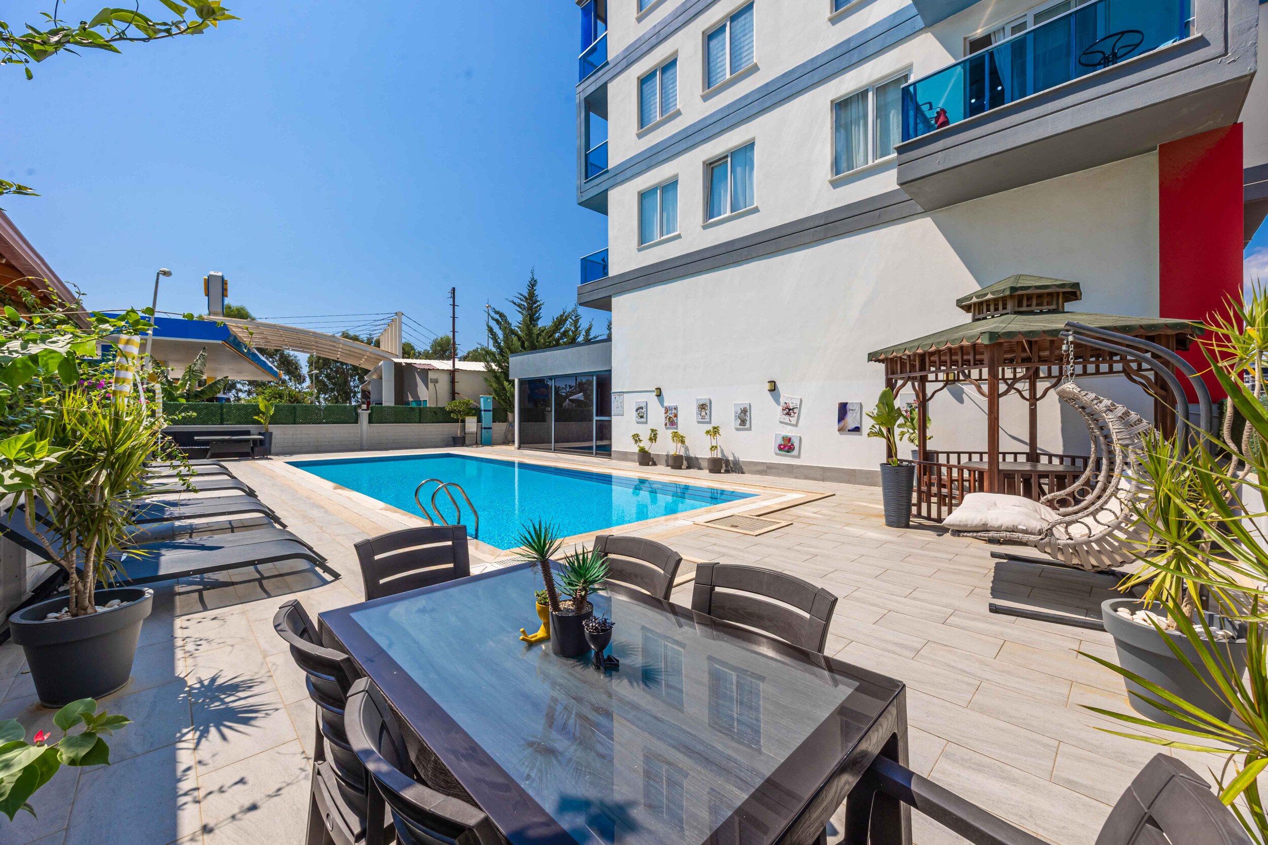 Pool with a gazebo and hanging chair beside residential buildings with apartments for sale in Kargicak
