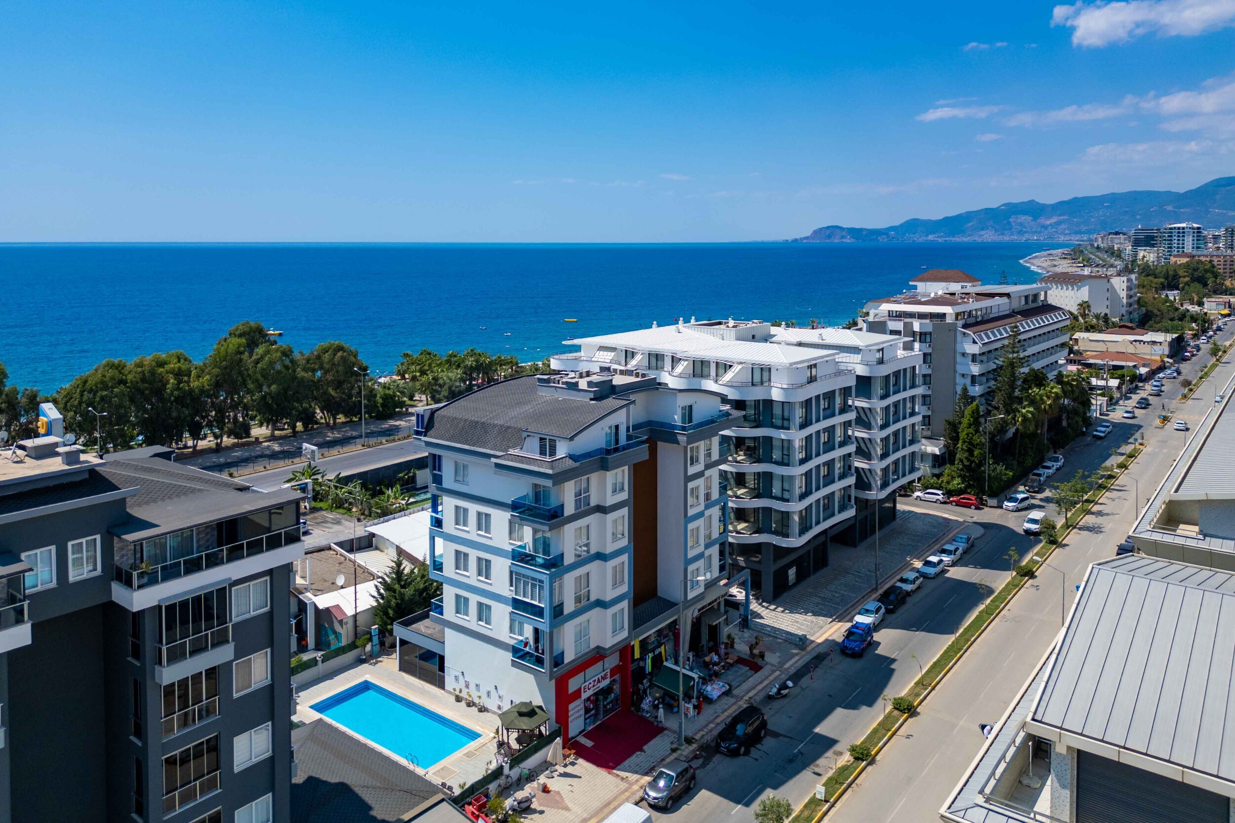 White apartment building with a pool and bay behind a duplex for sale