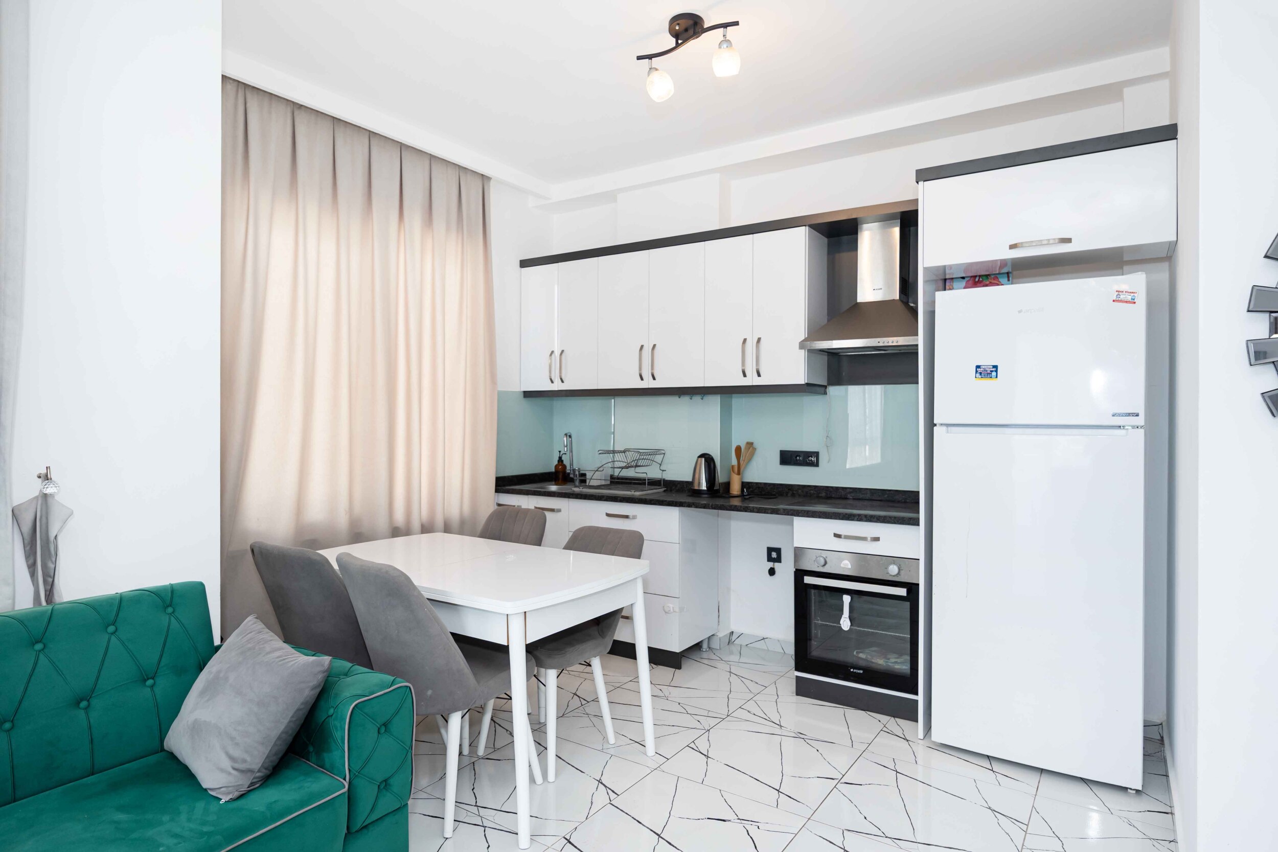 White kitchen with black worktop and turquoise backsplash in a penthouse in Kargicak