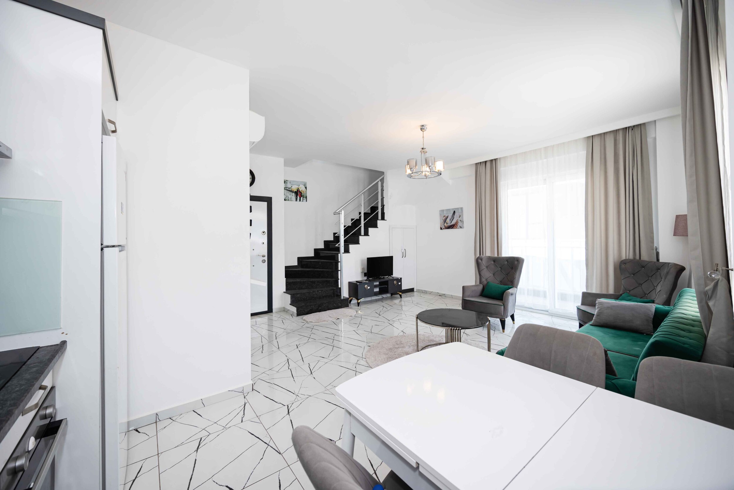 Open living room with dining area and green sofa in a residence for sale in Turkey