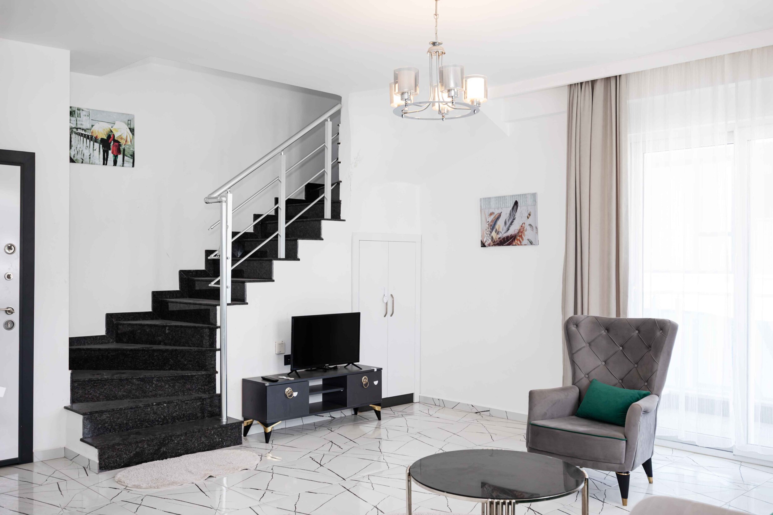 Black staircase, television and armchair beside a panoramic window in a penthouse