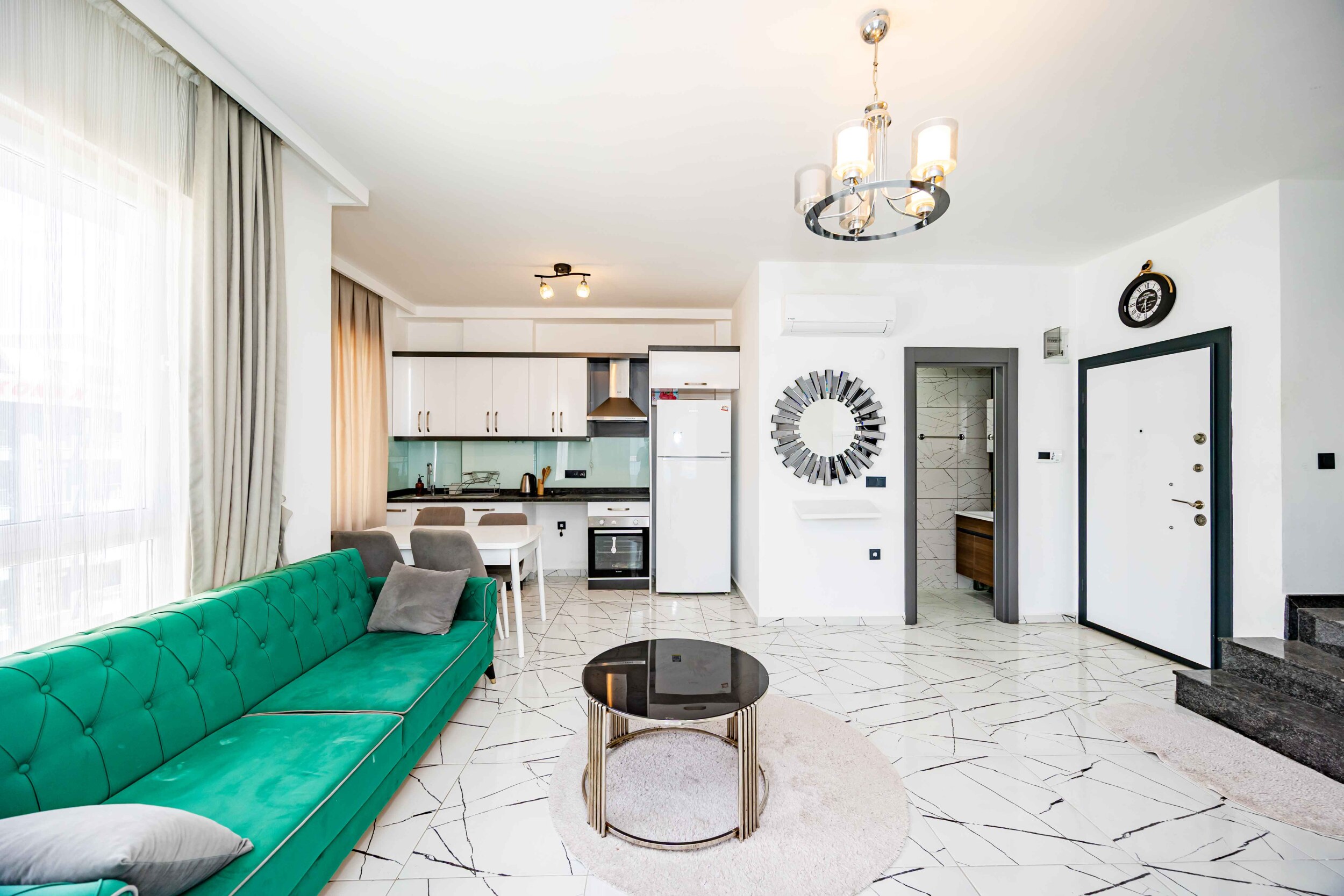 Green corner sofa, white kitchen and black staircase in a top-floor apartment in Turkey