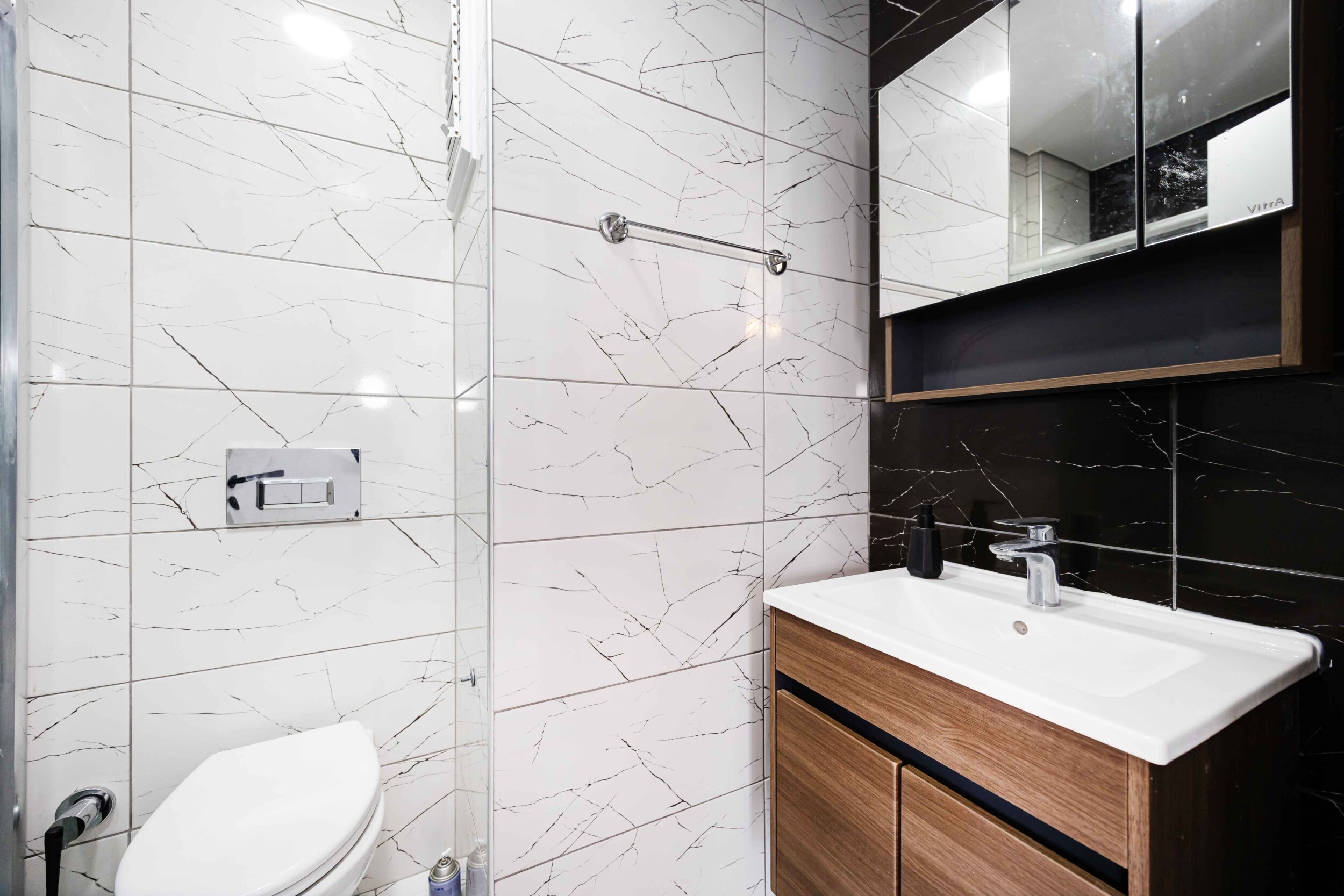 Bathroom with white sink, wooden vanity and glass shower partition