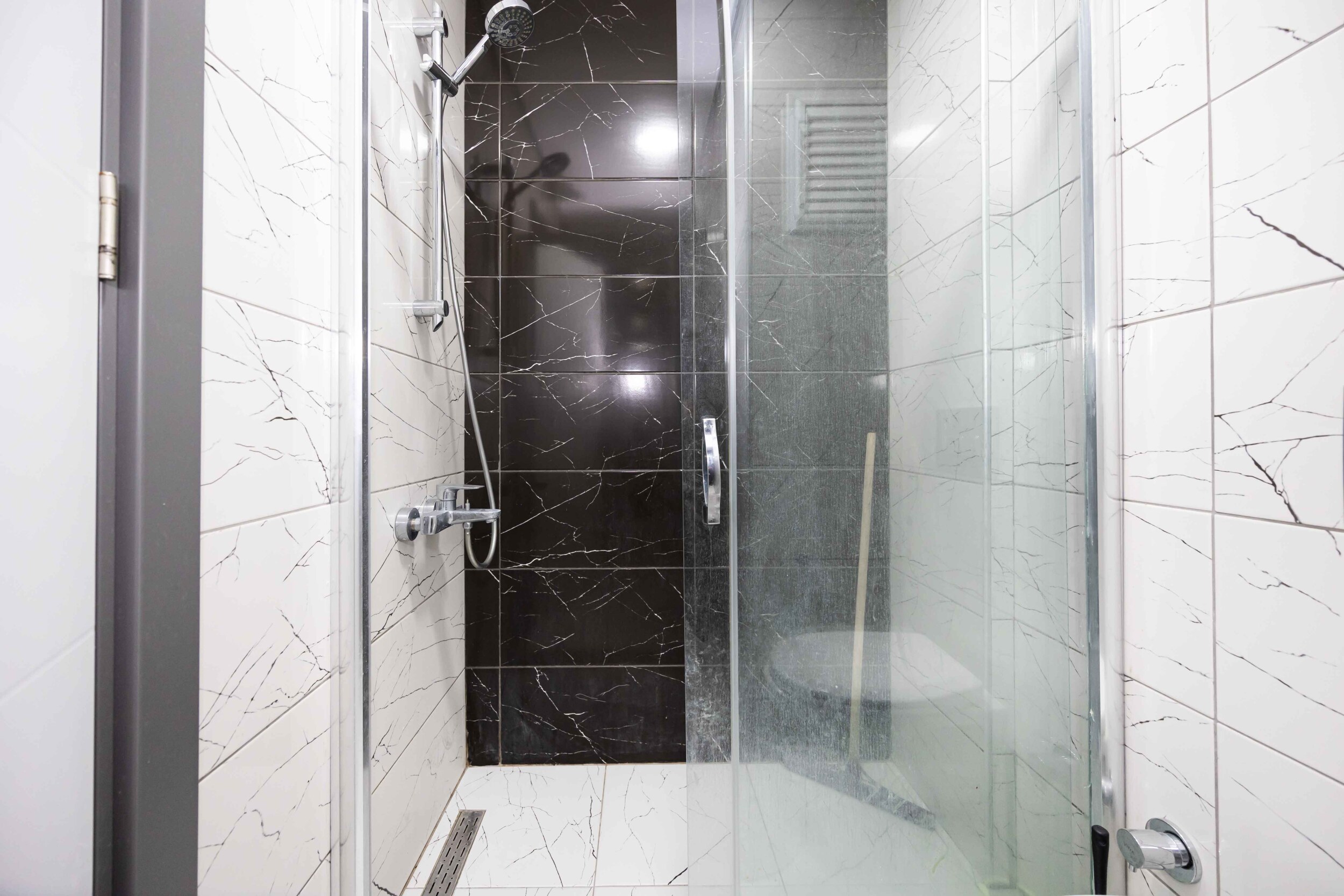 Glass shower enclosure with black accent tile in a penthouse in Kargicak