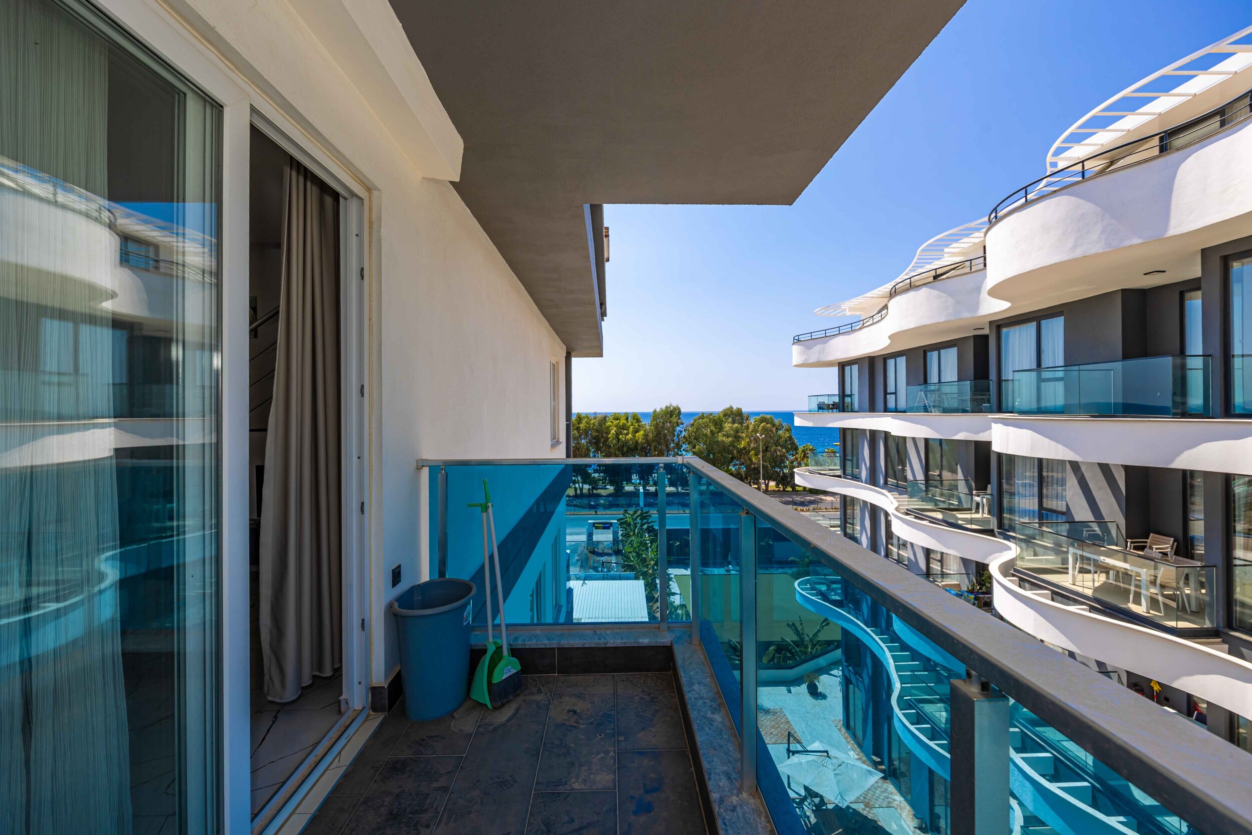 Balcony with glass railing overlooking the pool at a complex beside a duplex