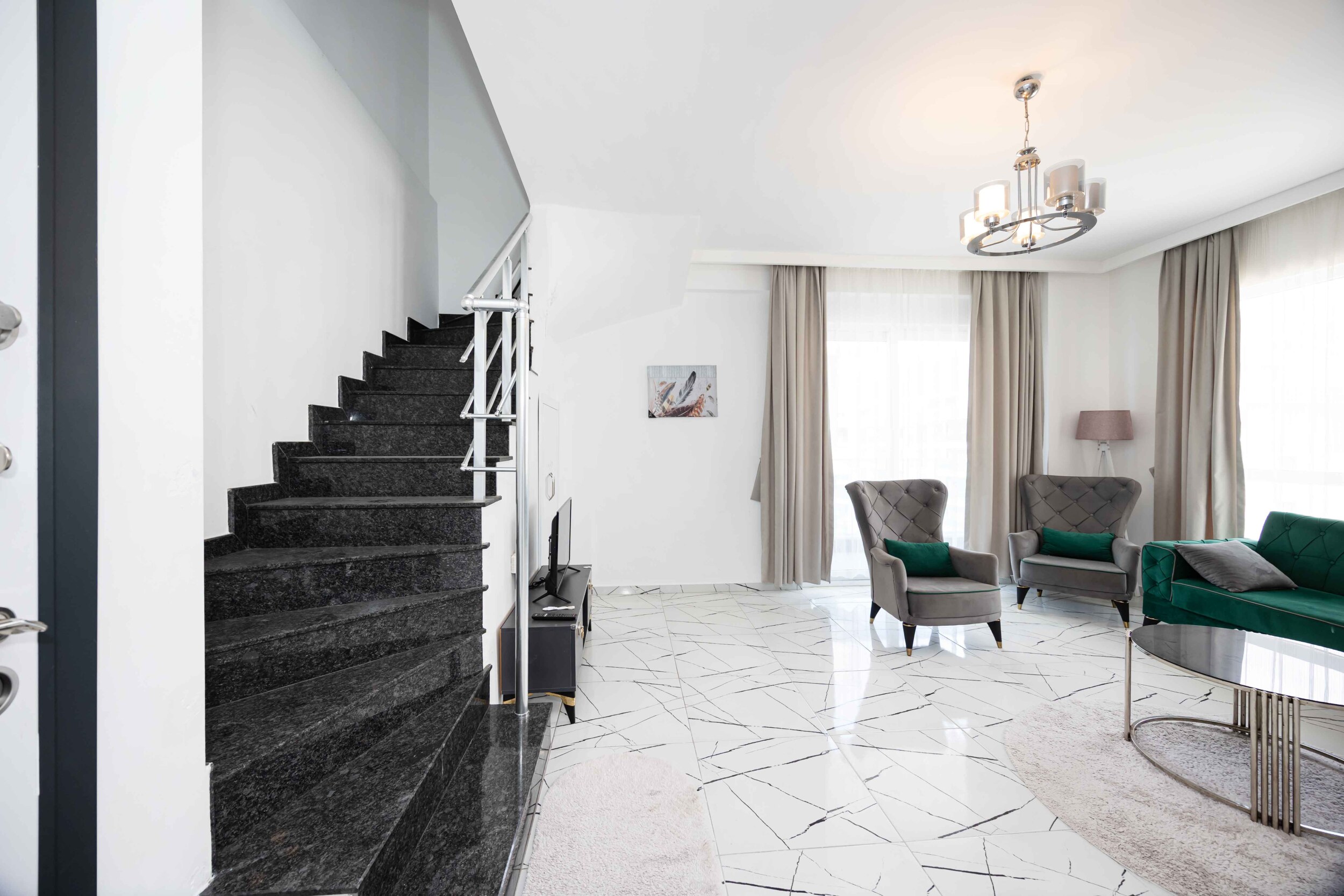 Black staircase, green sofa and panoramic windows in a penthouse for sale
