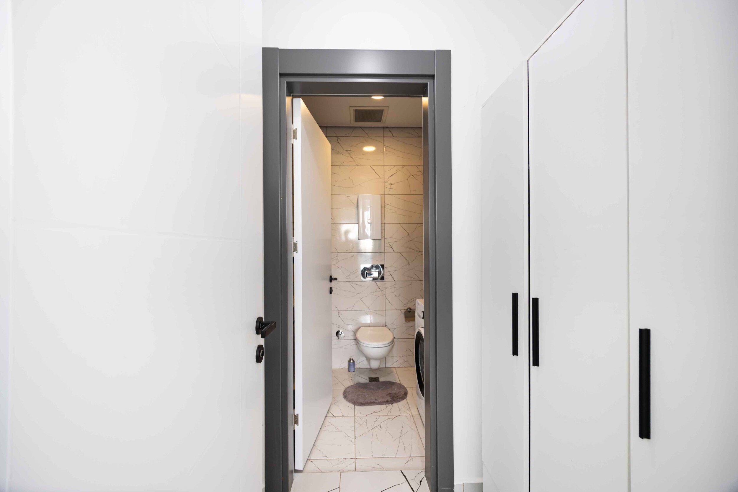 Bathroom with white washing machine and built-in wardrobe in a top-floor apartment
