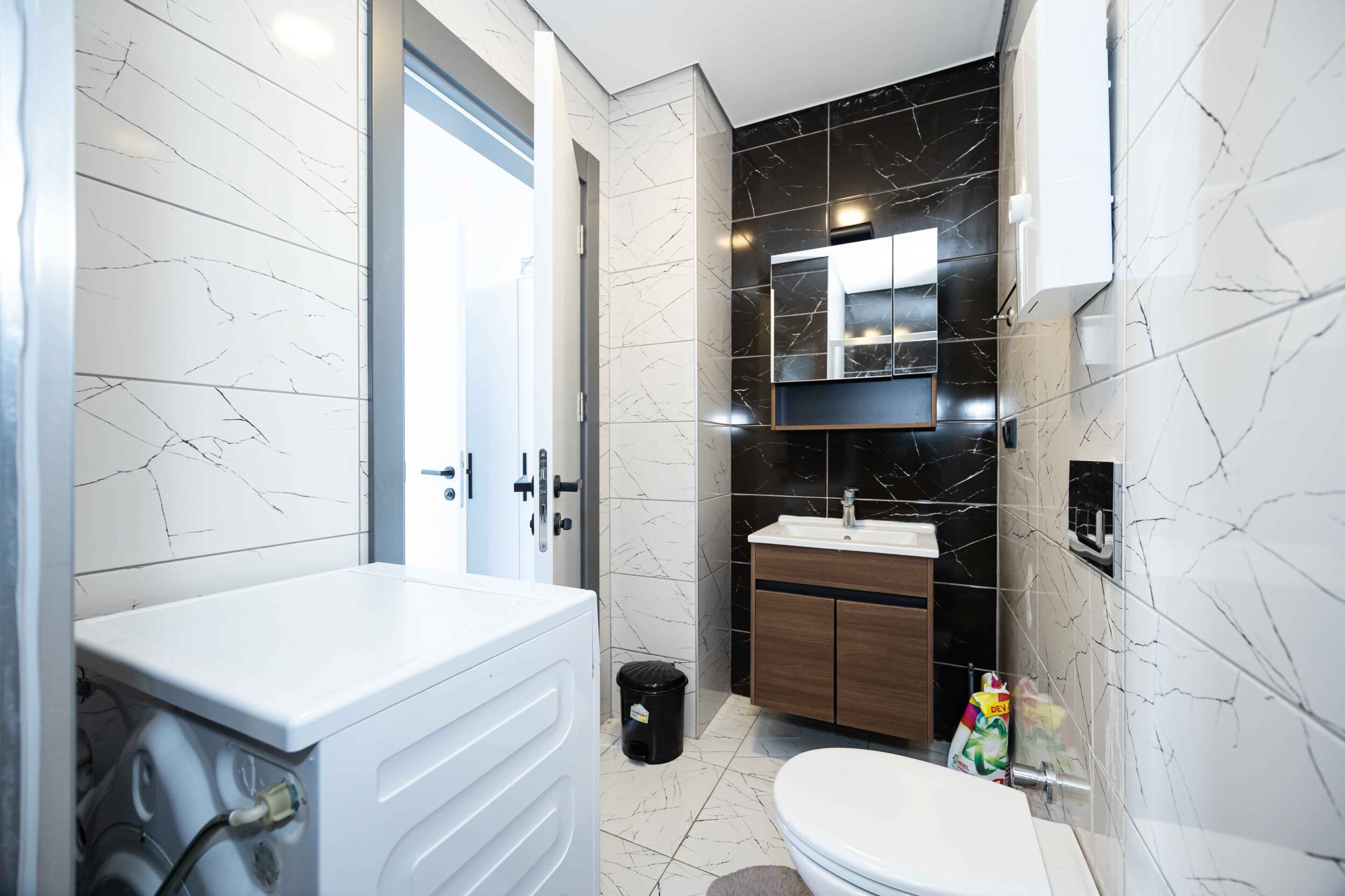 Sink with wooden vanity, mirror and washing machine in a bathroom