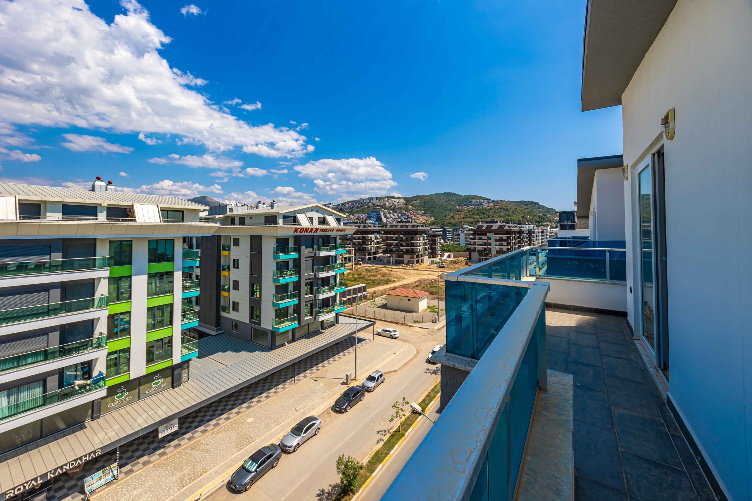 Long balcony with glass railing and residential buildings opposite