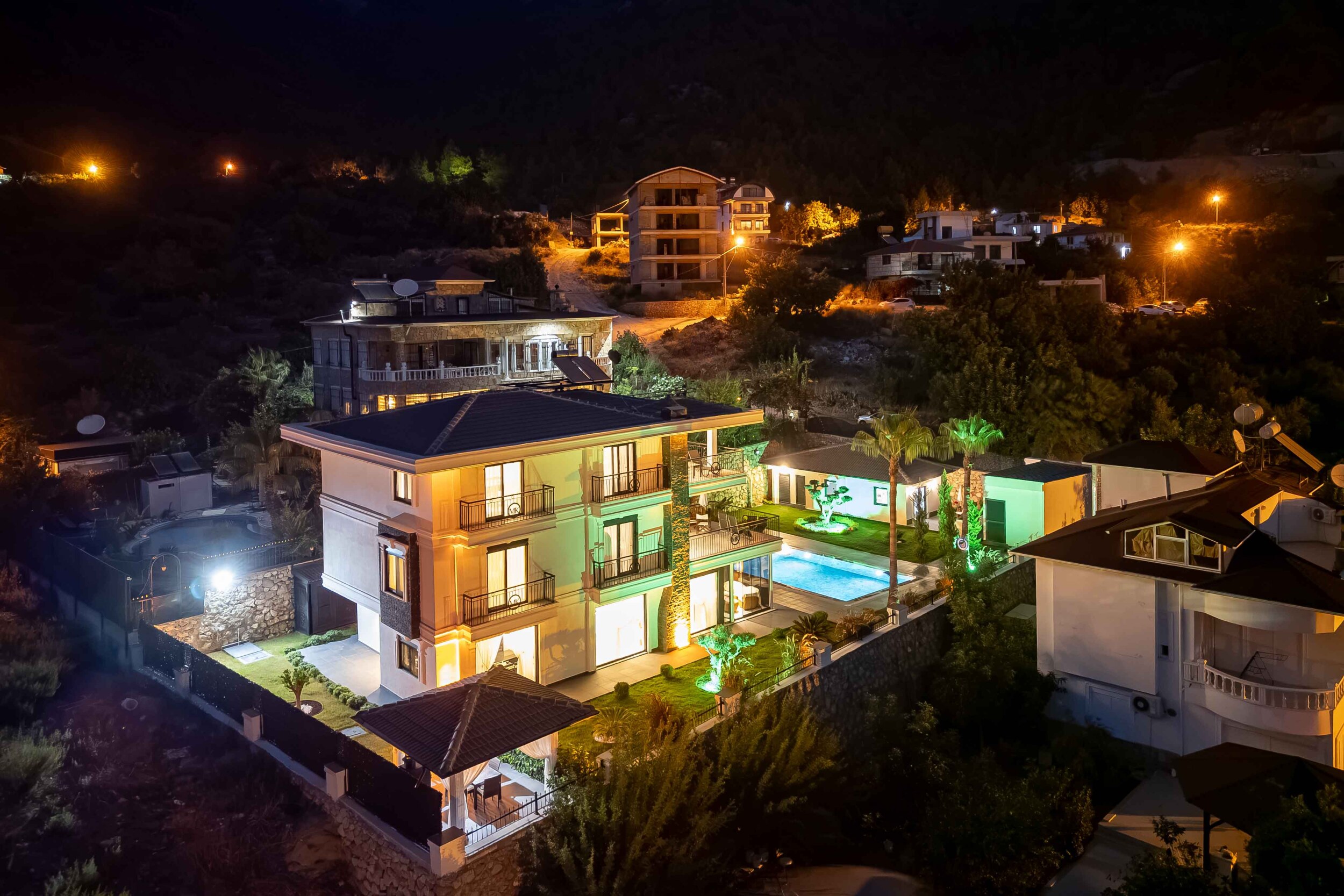 Многоэтажная вилла с бассейном и вечерней подсветкой в Турции продаётся среди горной застройки