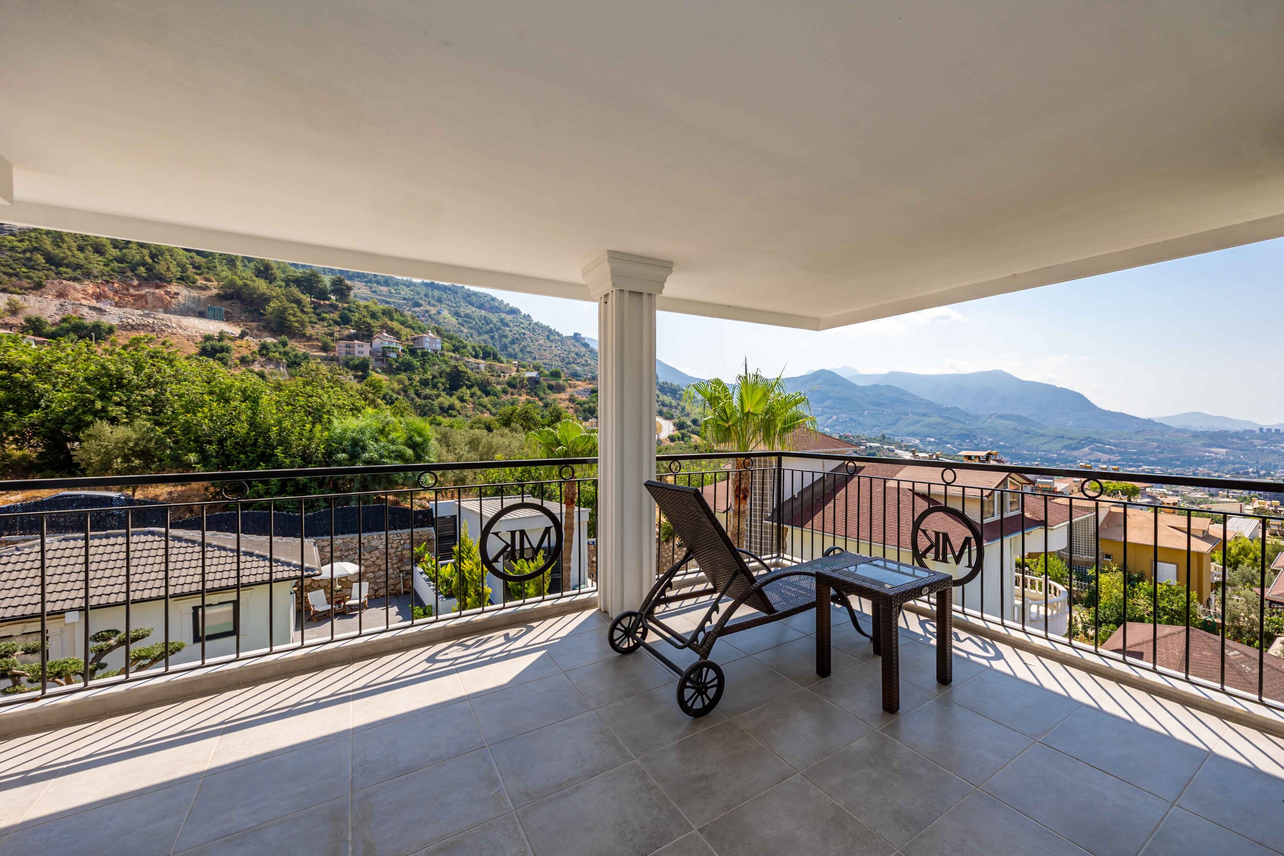 Крытая терраса с креслами, декоративным ограждением и видом на горы в вилле в Оба, Турция