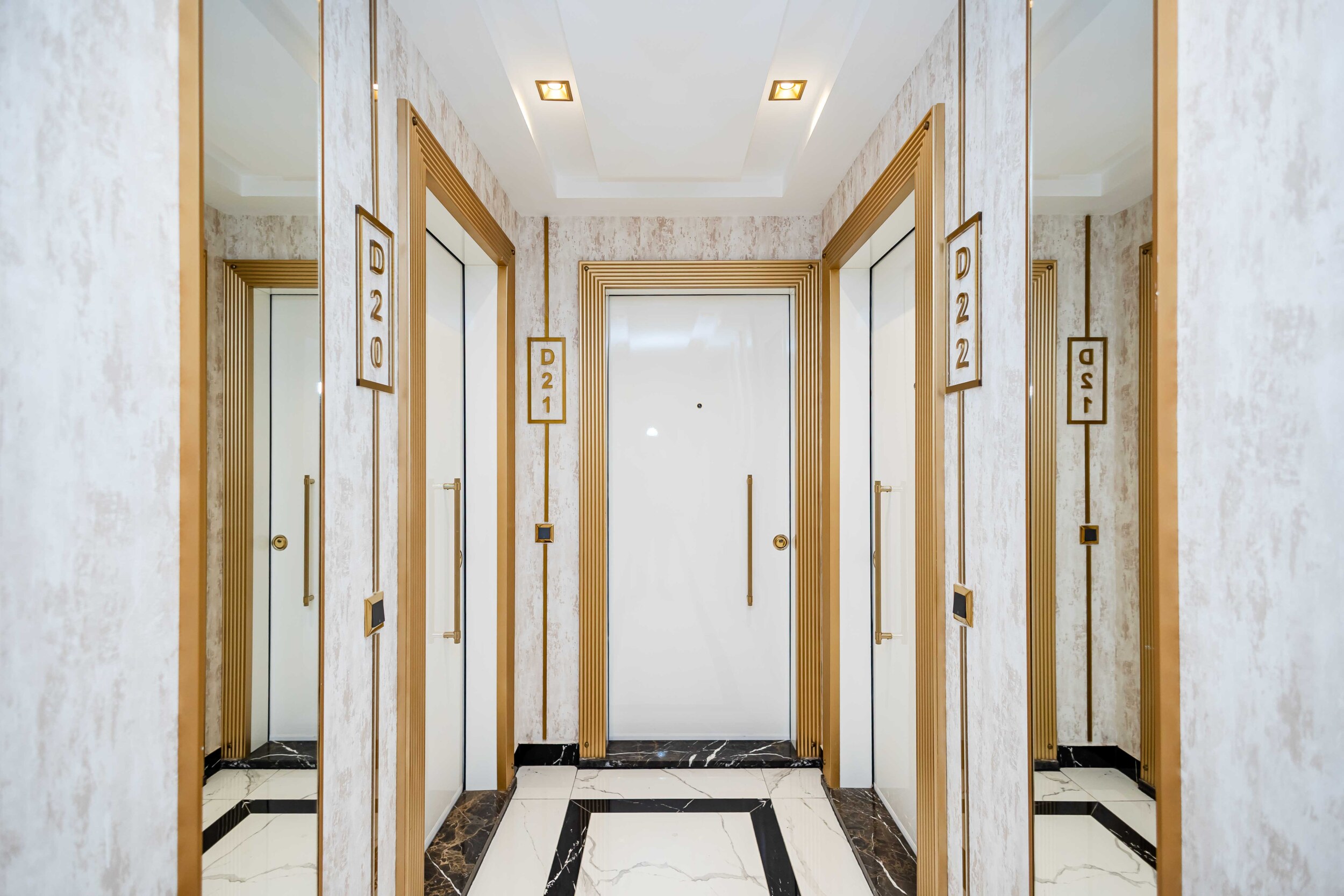 Lobby with gold-trimmed lifts and mirrored panels in a complex with a top-floor apartment in Turkey
